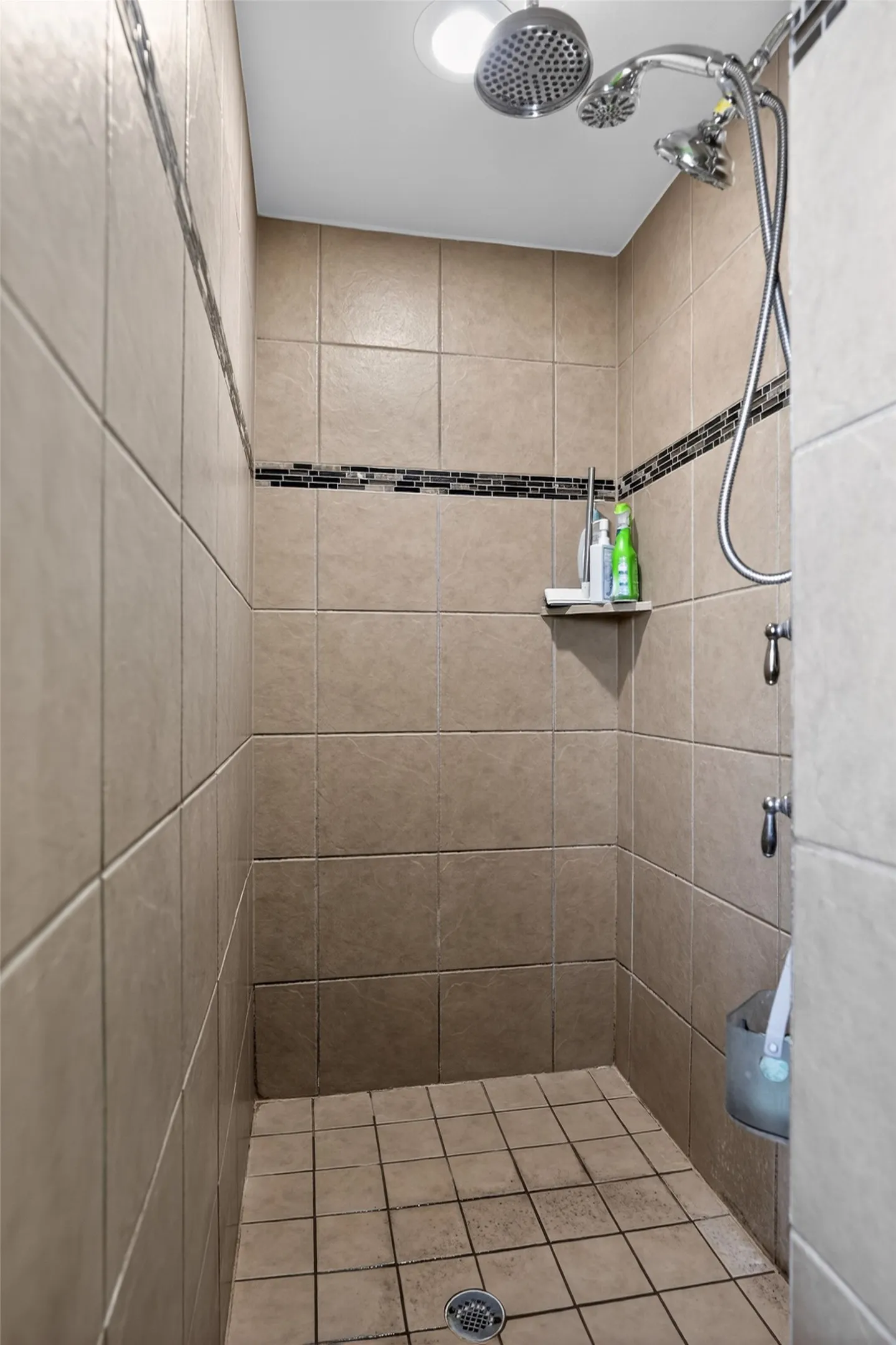 Tiled shower stall featuring an integrated mosaic tile accent band