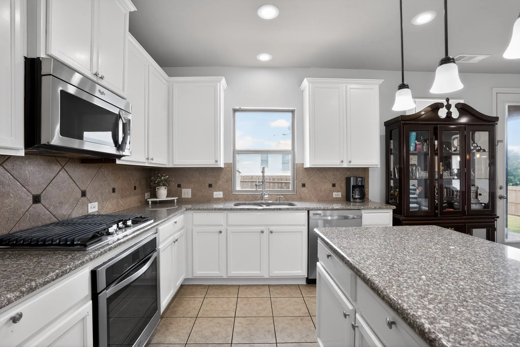 Kitchen featuring white cabinetry, granite-finish countertops, stainless steel appliances, a tile backsplash, and tile flooring