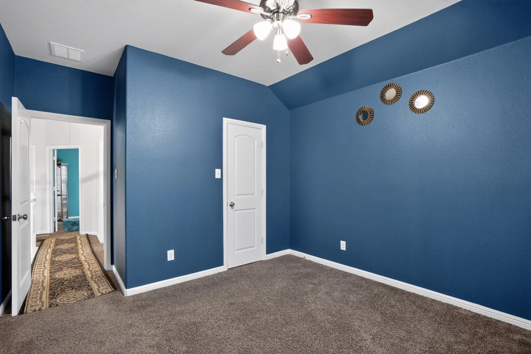 Room with textured blue walls, white trim, and brown carpet flooring
