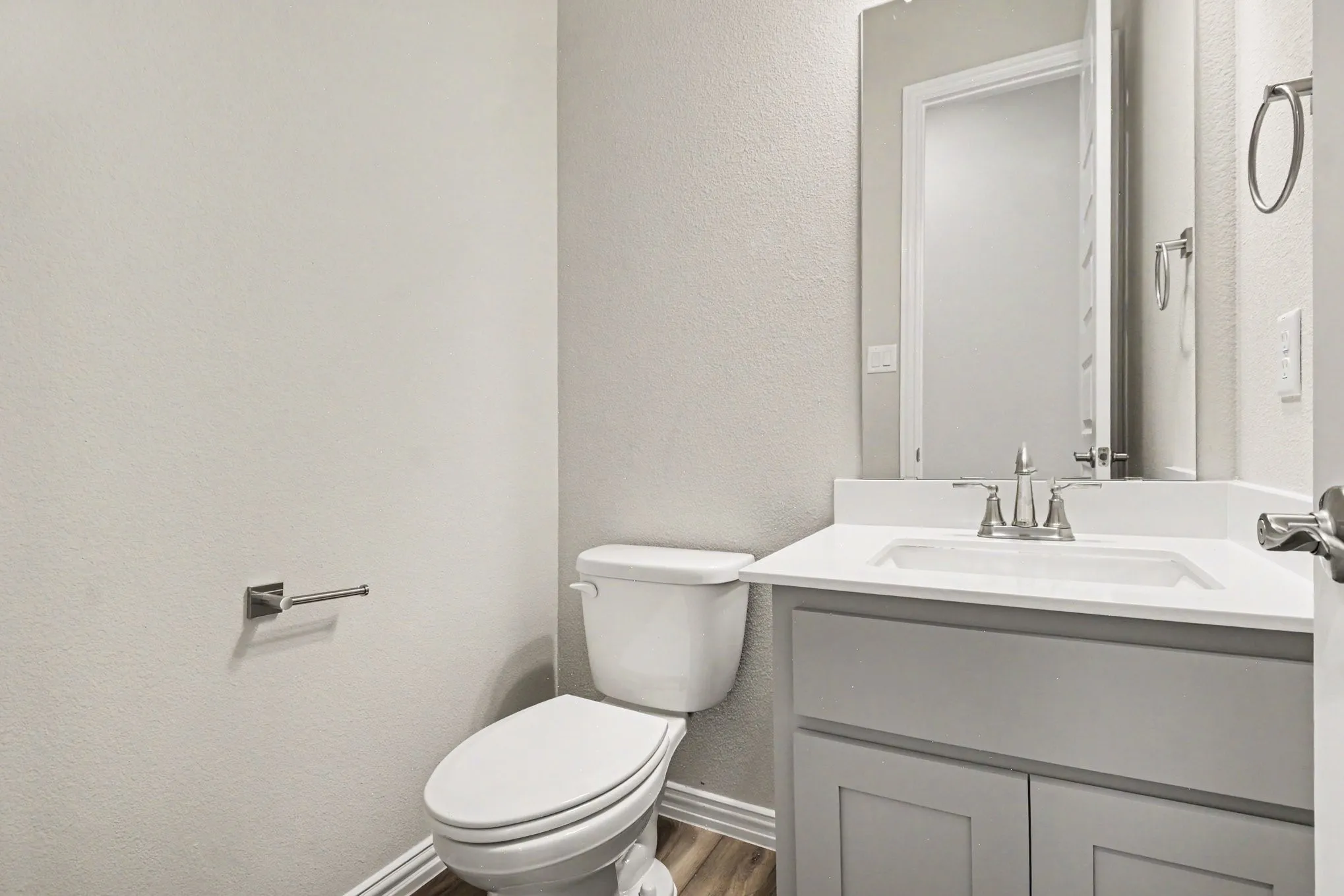 Bathroom vanity with a white countertop and integrated sink, brushed nickel faucet, and a large wall mirror