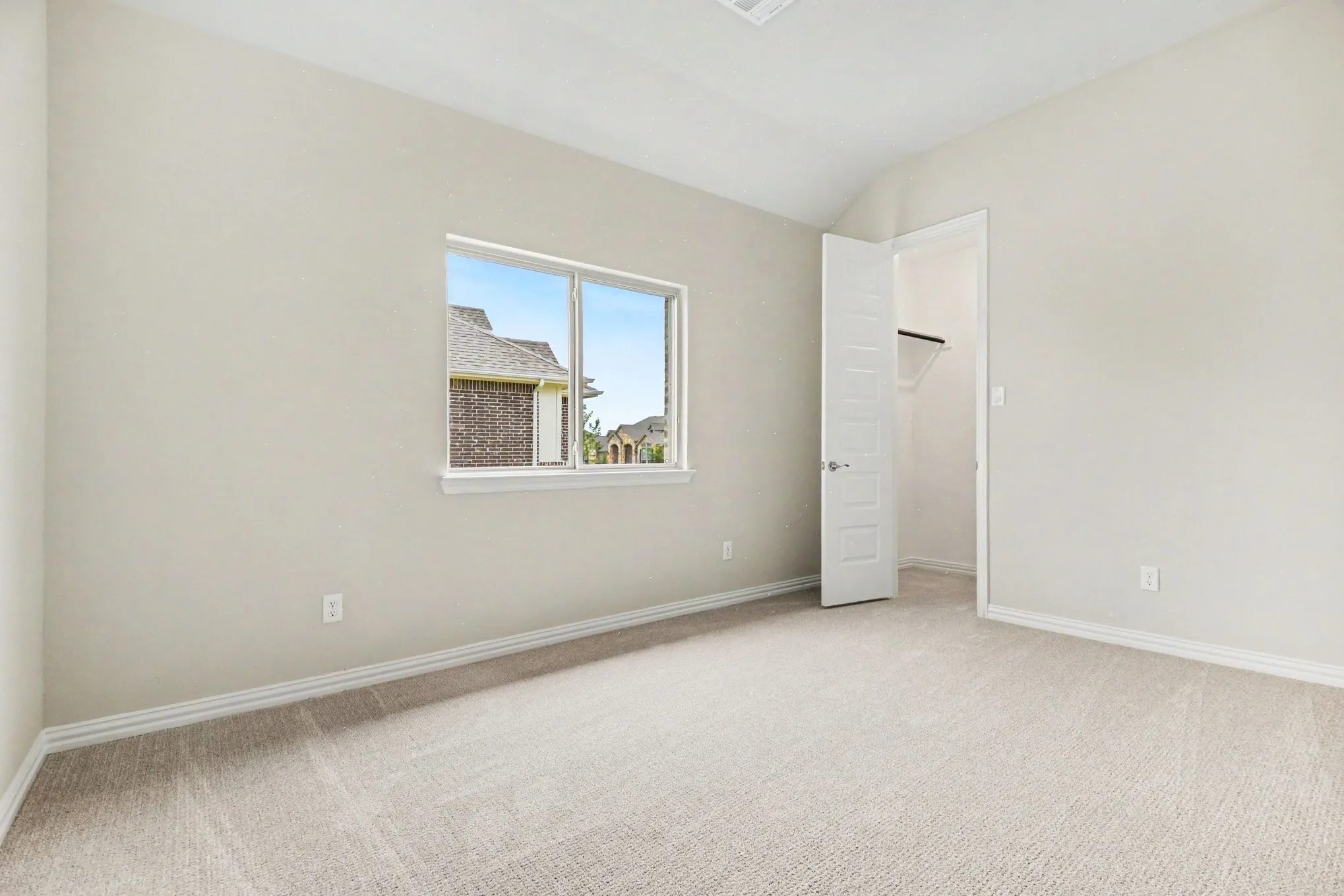 Carpeted room with a vaulted ceiling and a single window