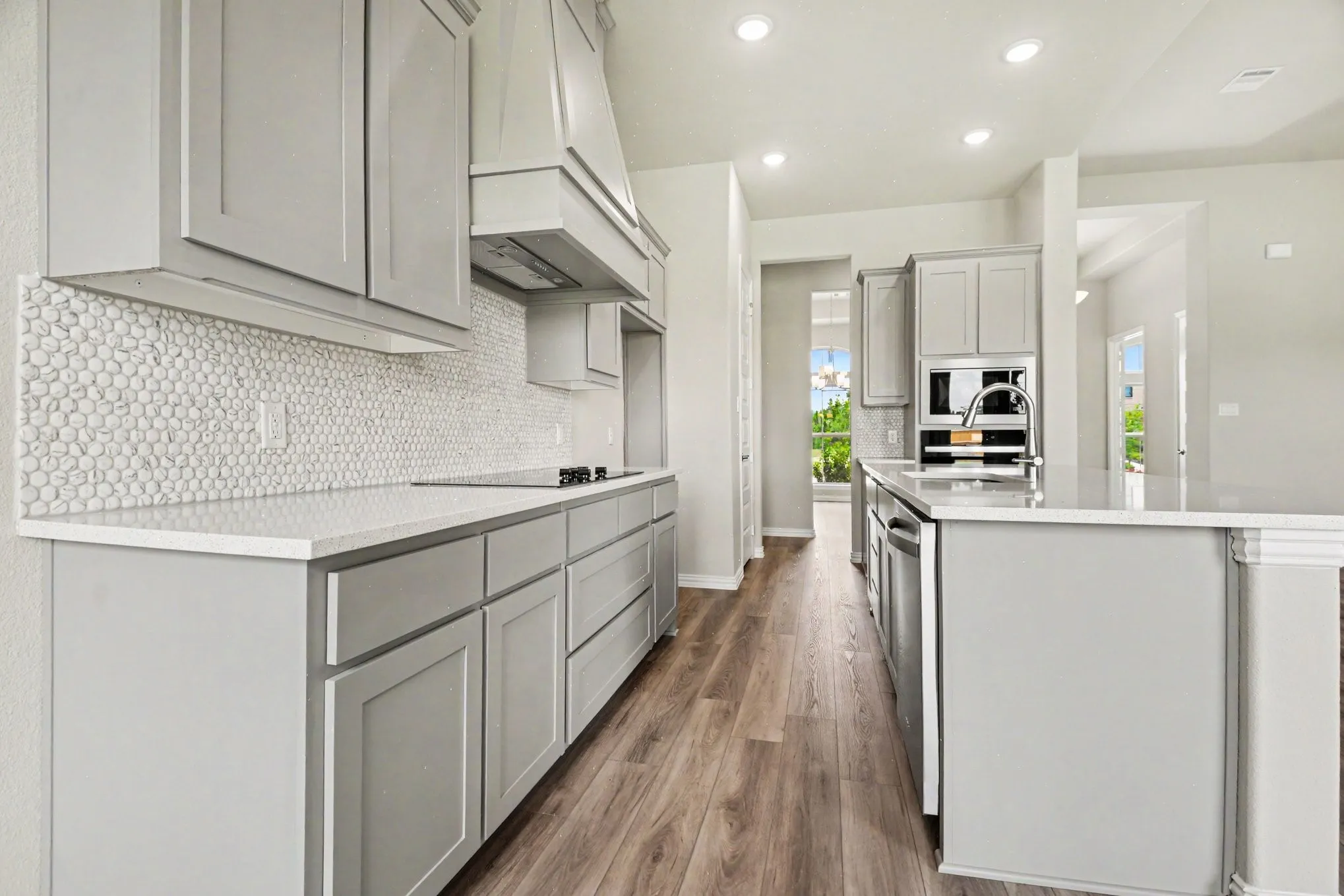 Modern kitchen featuring light gray cabinetry, light-toned countertops, and wood-finish flooring