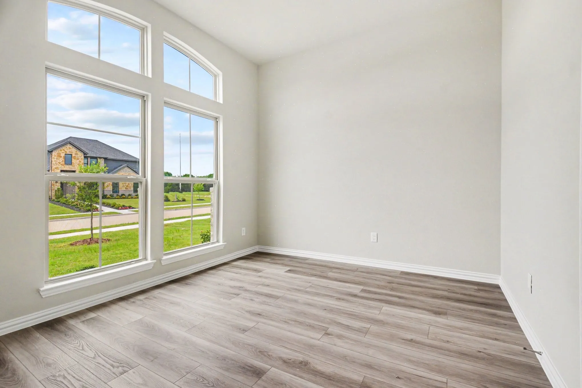 Room featuring a vaulted ceiling and extensive multi-pane windows with an arched transom