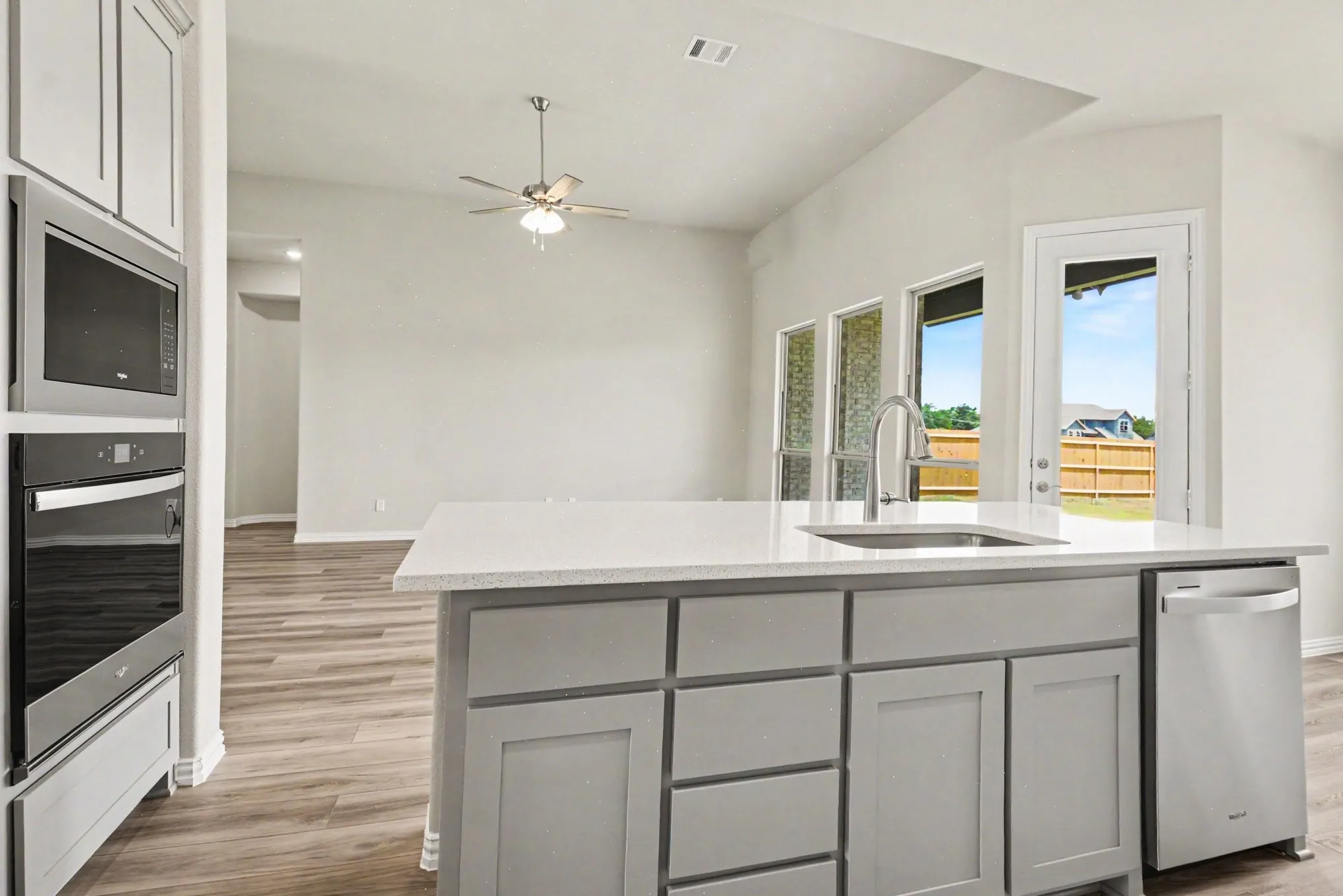 Kitchen island with a built-in sink, stainless steel dishwasher, and light-toned countertop