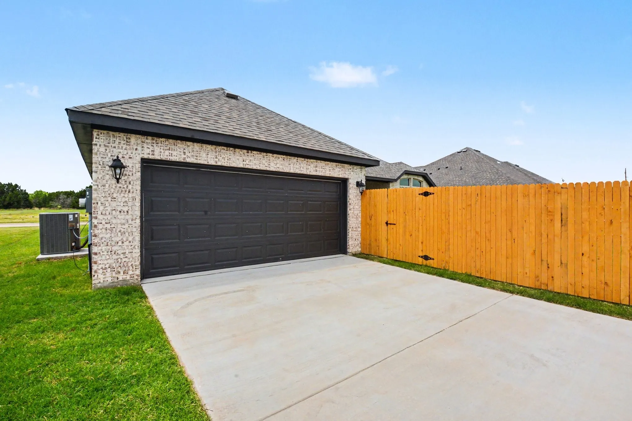 Attached garage with a dark sectional door, light brick exterior, and a dark shingle roof