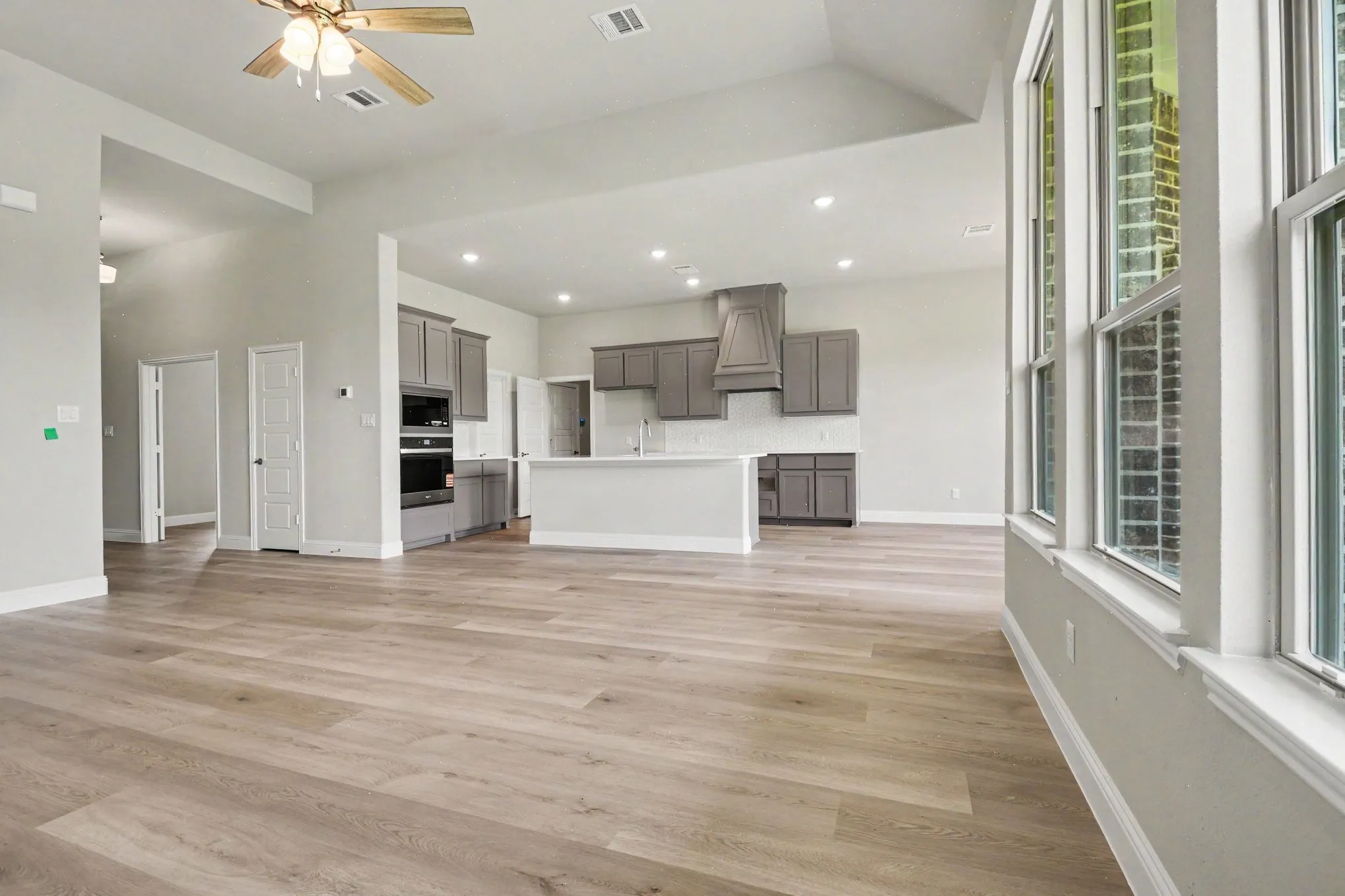 Open-concept living space featuring wood-finish flooring, recessed lighting, and high ceilings
