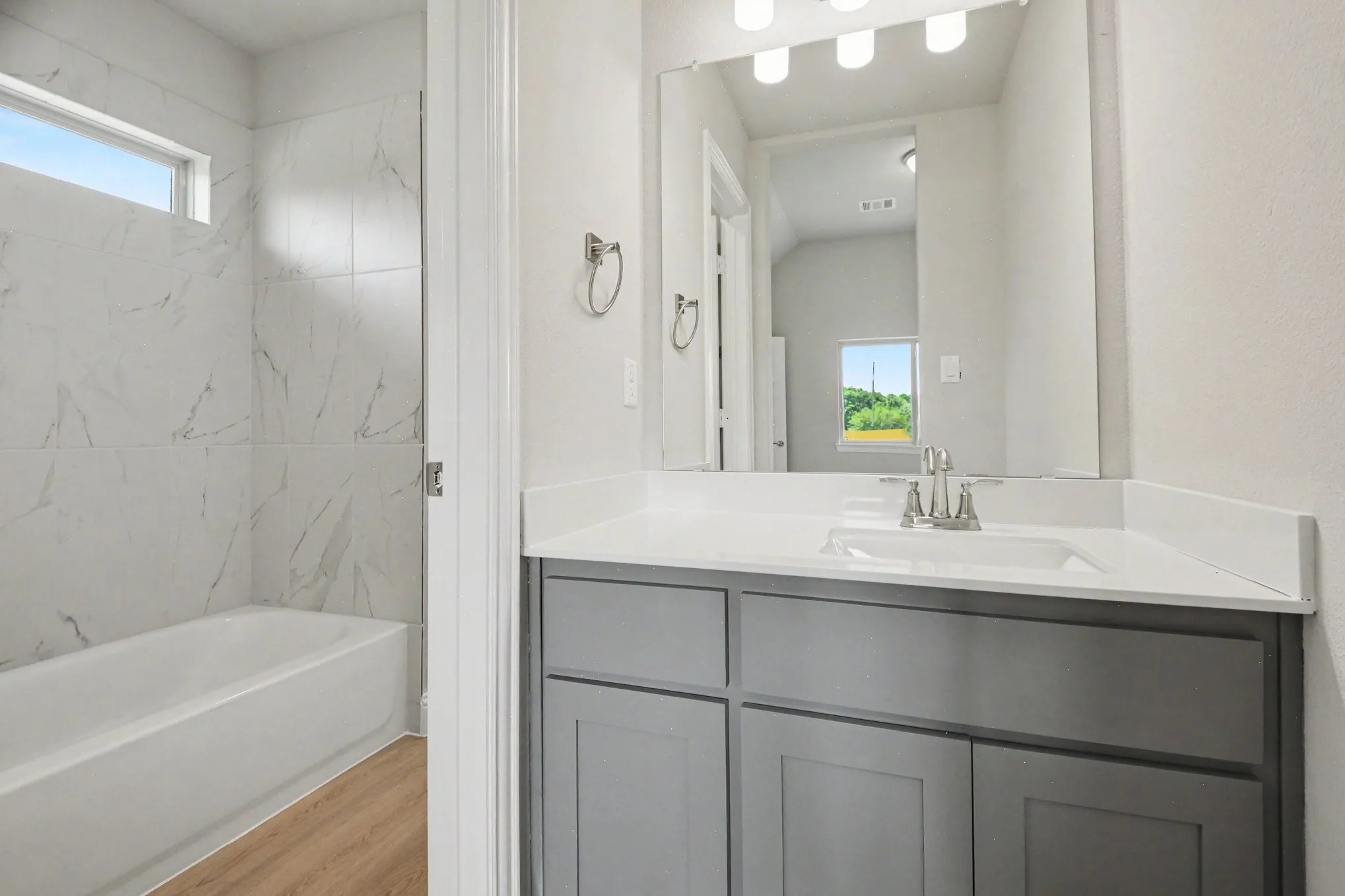 Bathroom vanity featuring a light gray cabinet, white countertop, and brushed nickel hardware