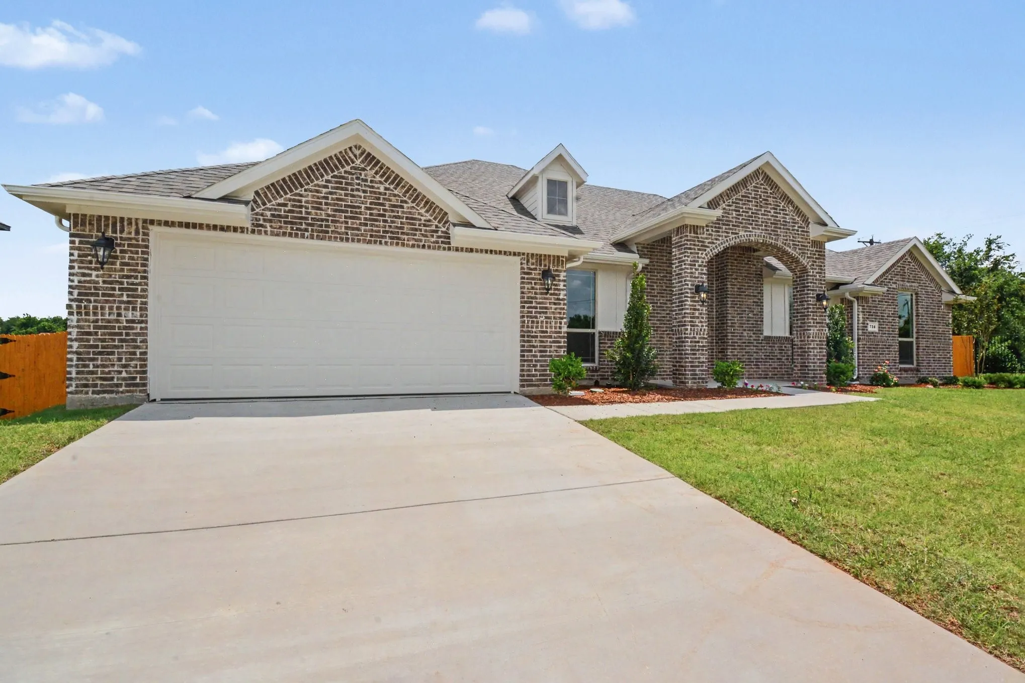 Brick facade residence featuring an arched portico entry