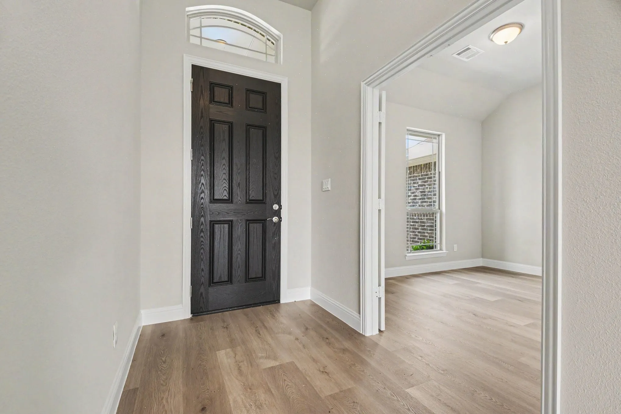 Entryway featuring a dark paneled door with an arched transom window
