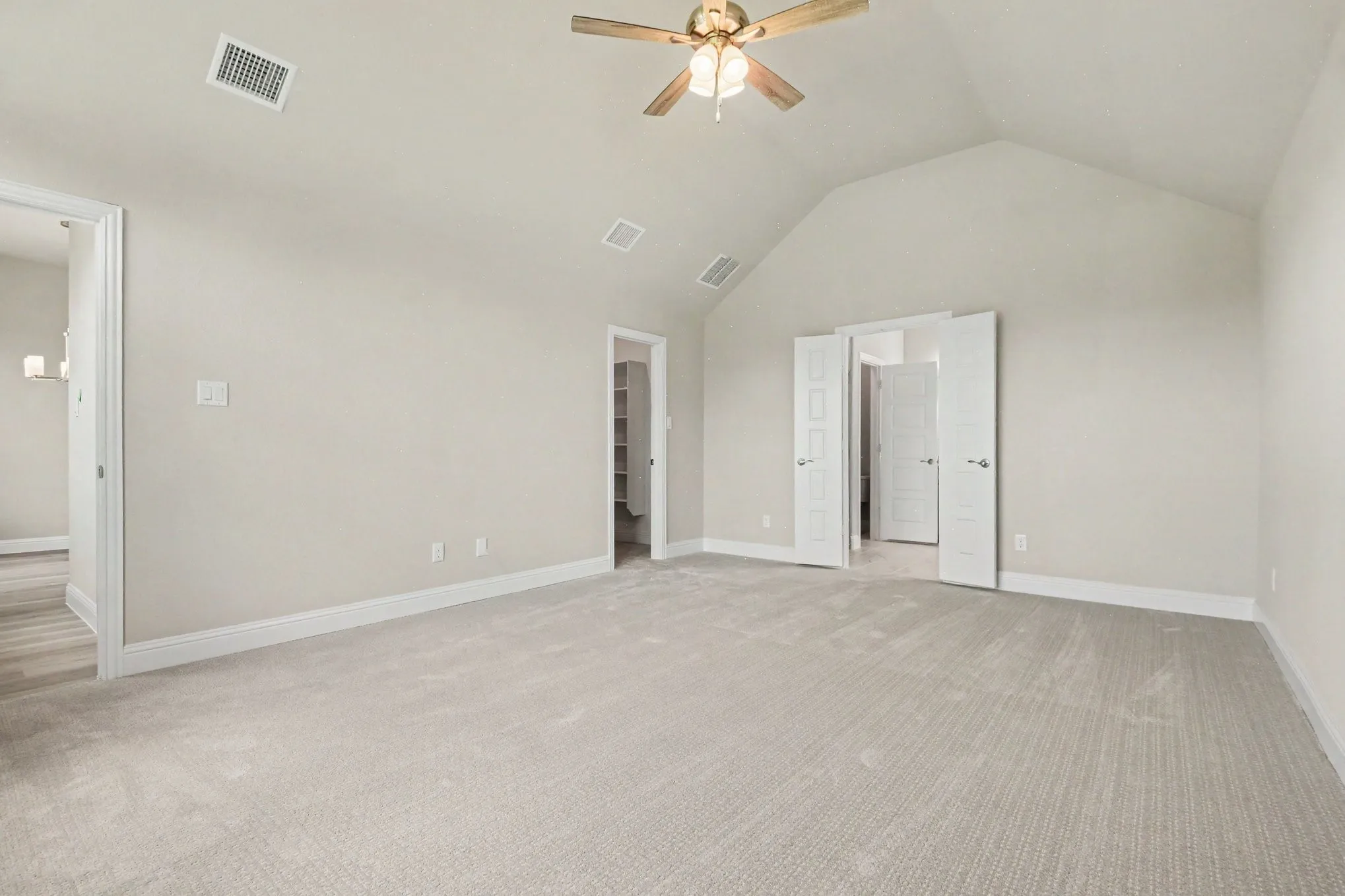 Expansive room with vaulted ceiling and light-toned carpeting