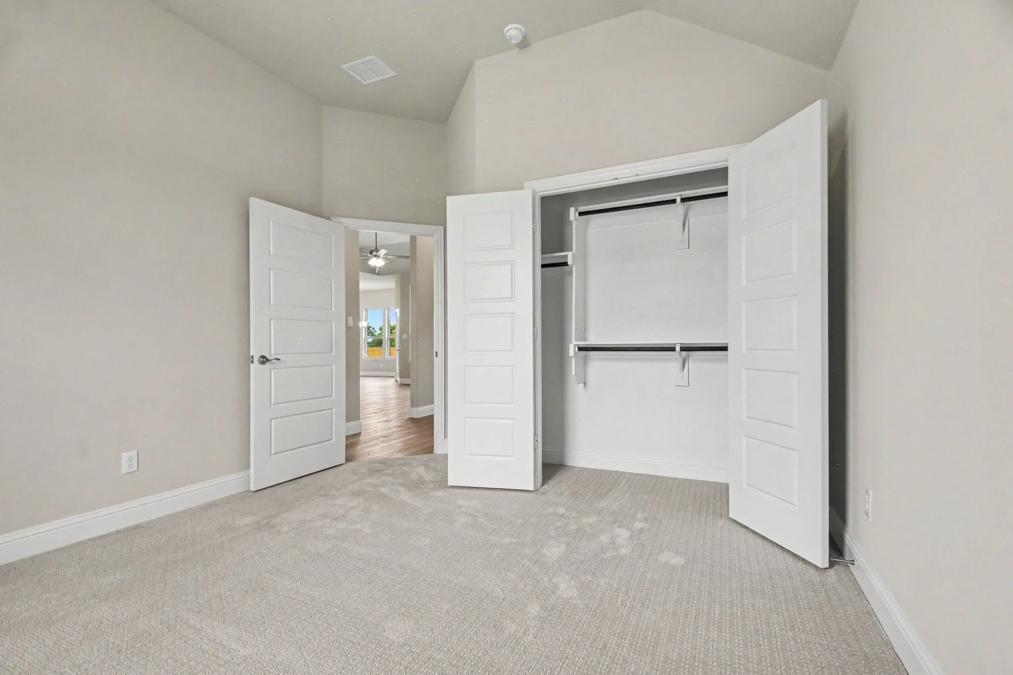 Bedroom featuring vaulted ceilings, light gray wall paint, white trim, and light gray carpet flooring