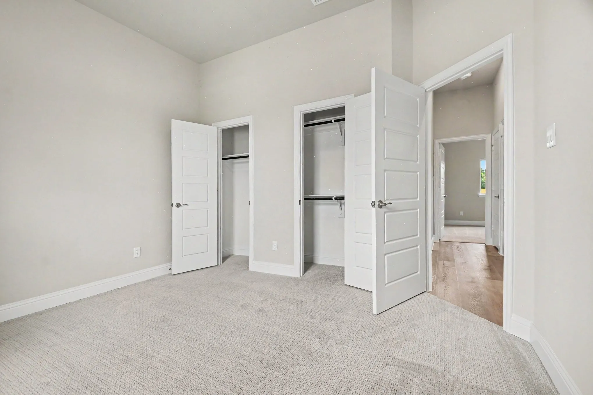 Carpeted room featuring two closets with white panel doors and chrome hardware