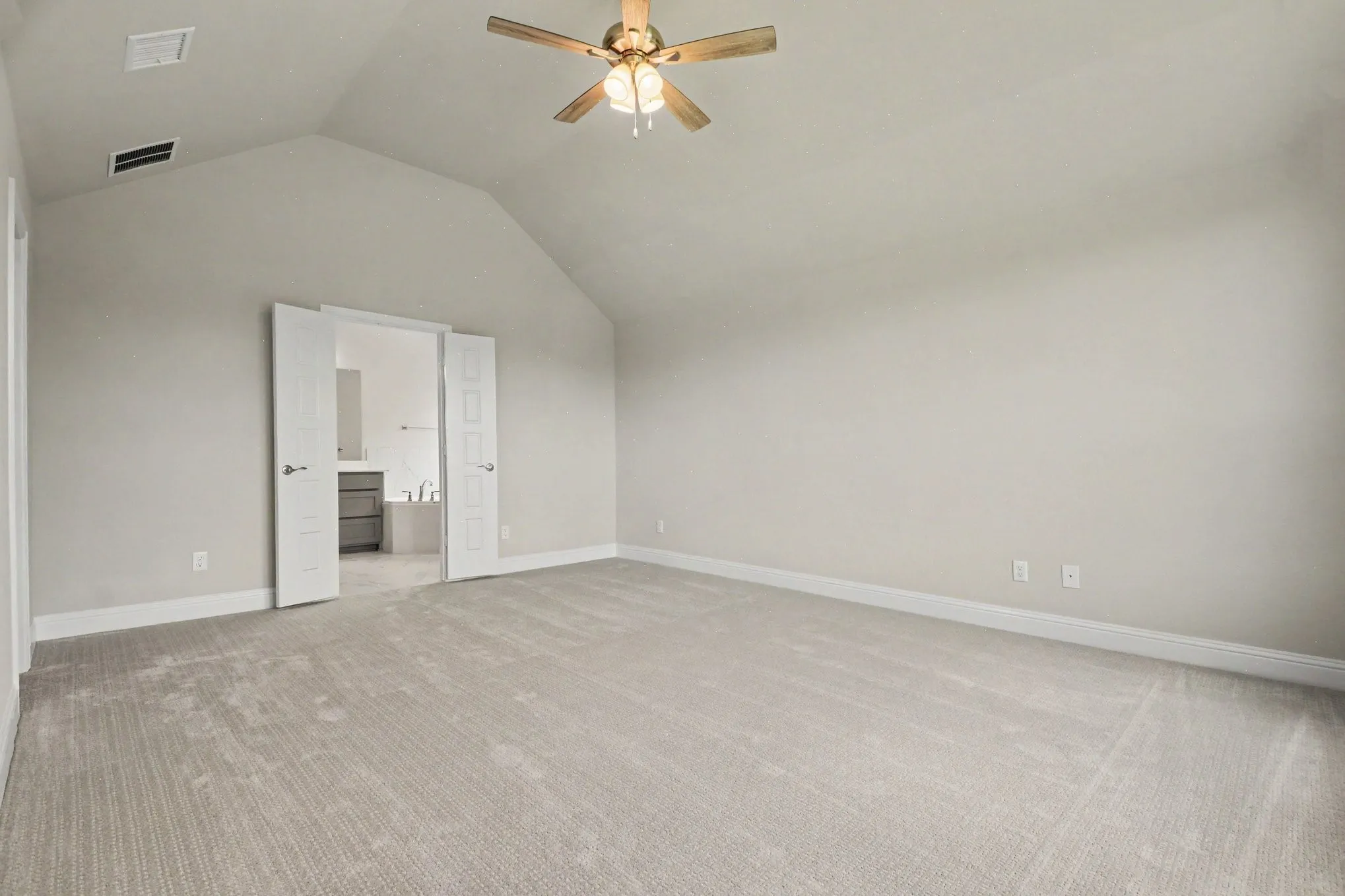 Spacious room featuring vaulted ceilings, light-toned carpeting, a ceiling fan with integrated lighting, and white baseboards
