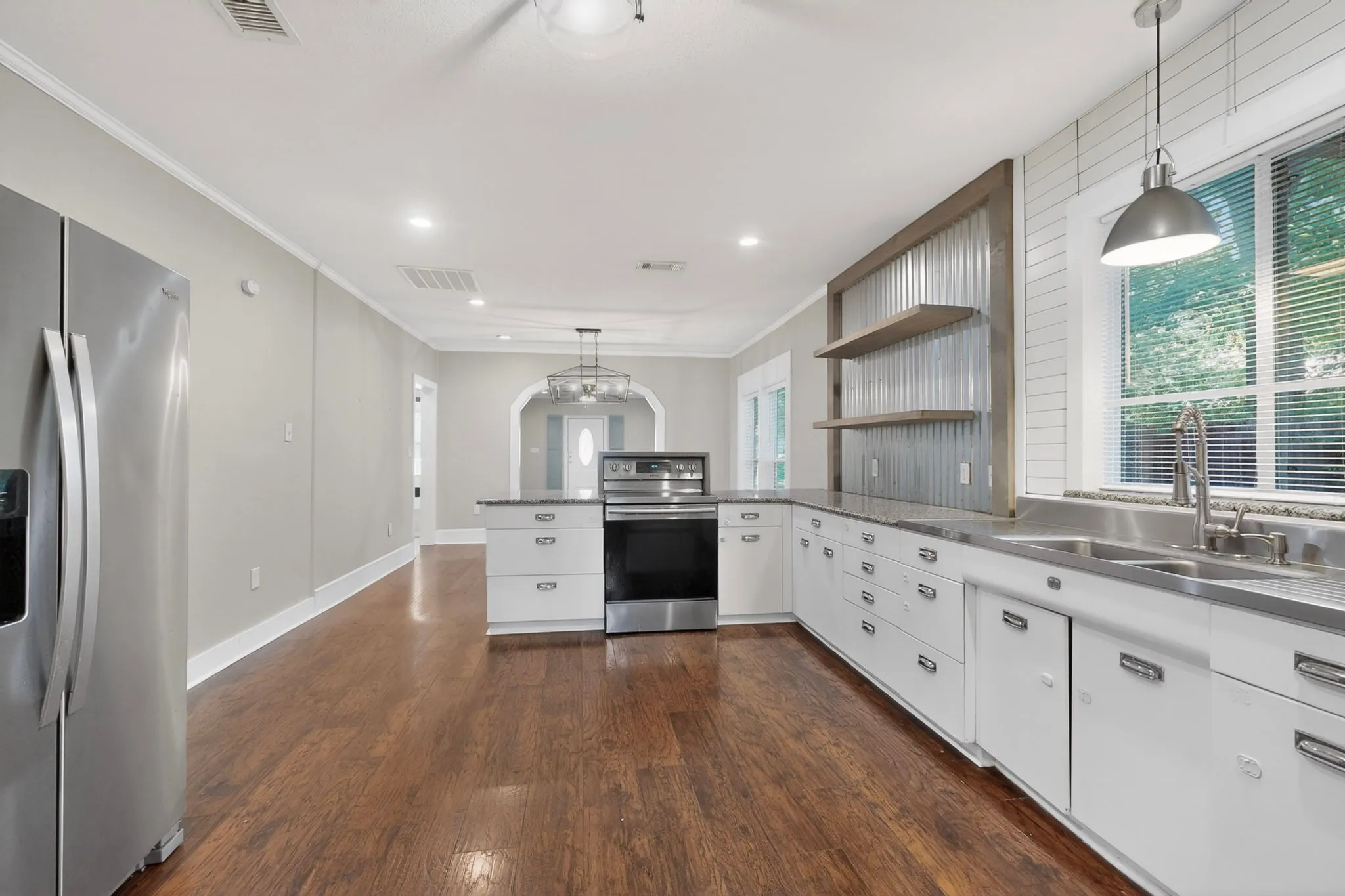 Kitchen featuring wood-finish flooring, white cabinetry, stainless steel appliances, and a central island