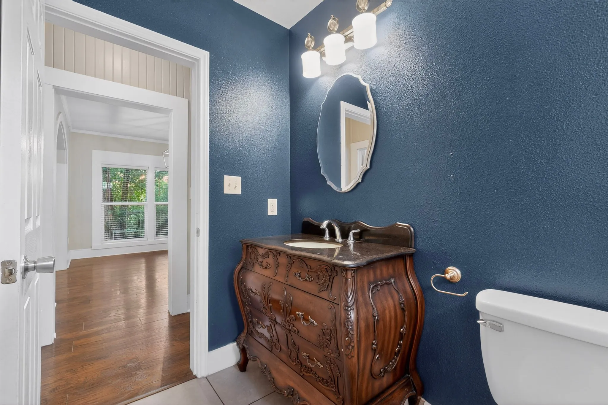 Bathroom featuring a decorative vanity with an integrated sink, an ornate mirror, and a three-light vanity fixture
