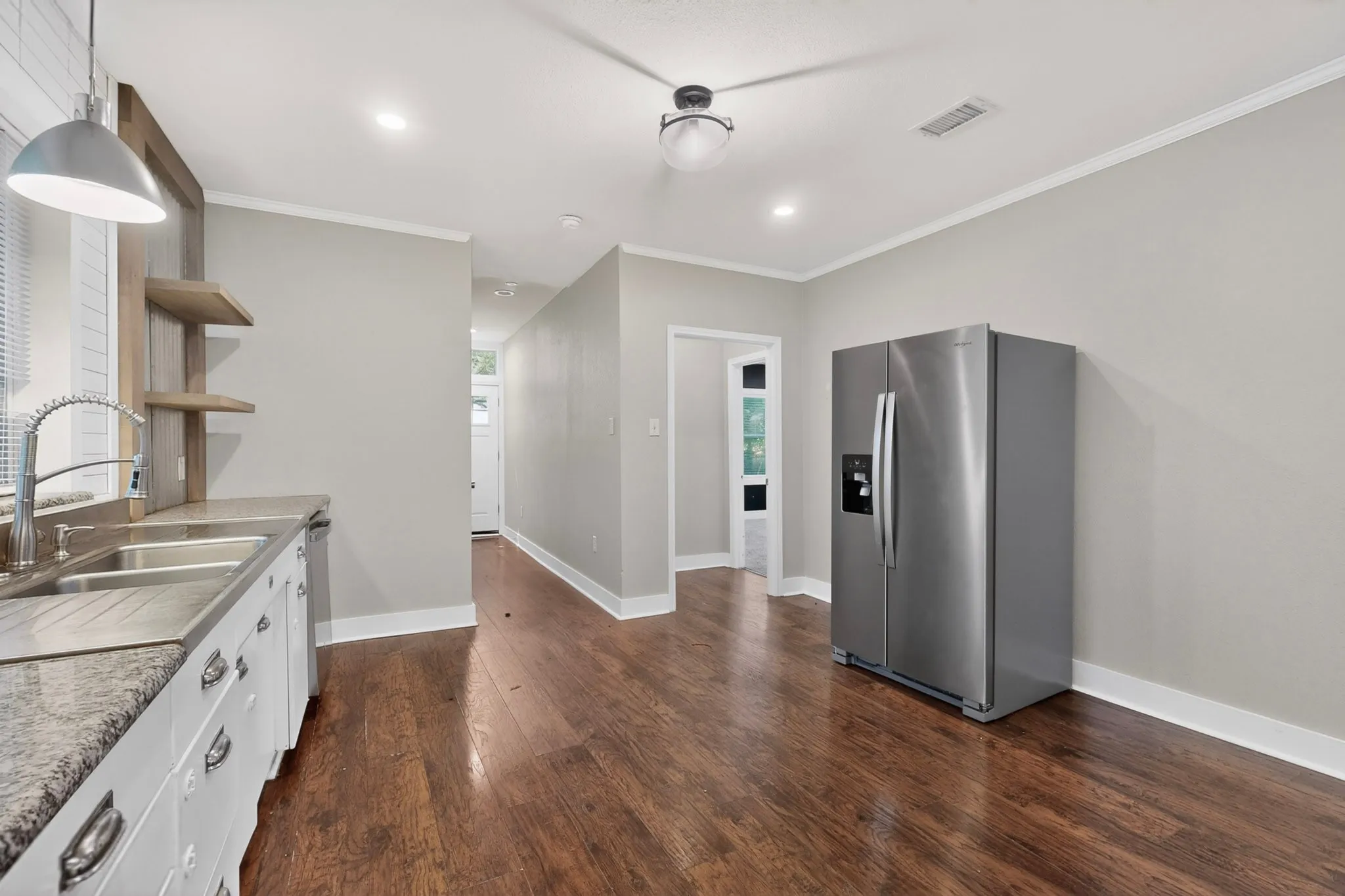 Kitchen featuring wood-finish flooring, light gray walls, white baseboards, and crown molding