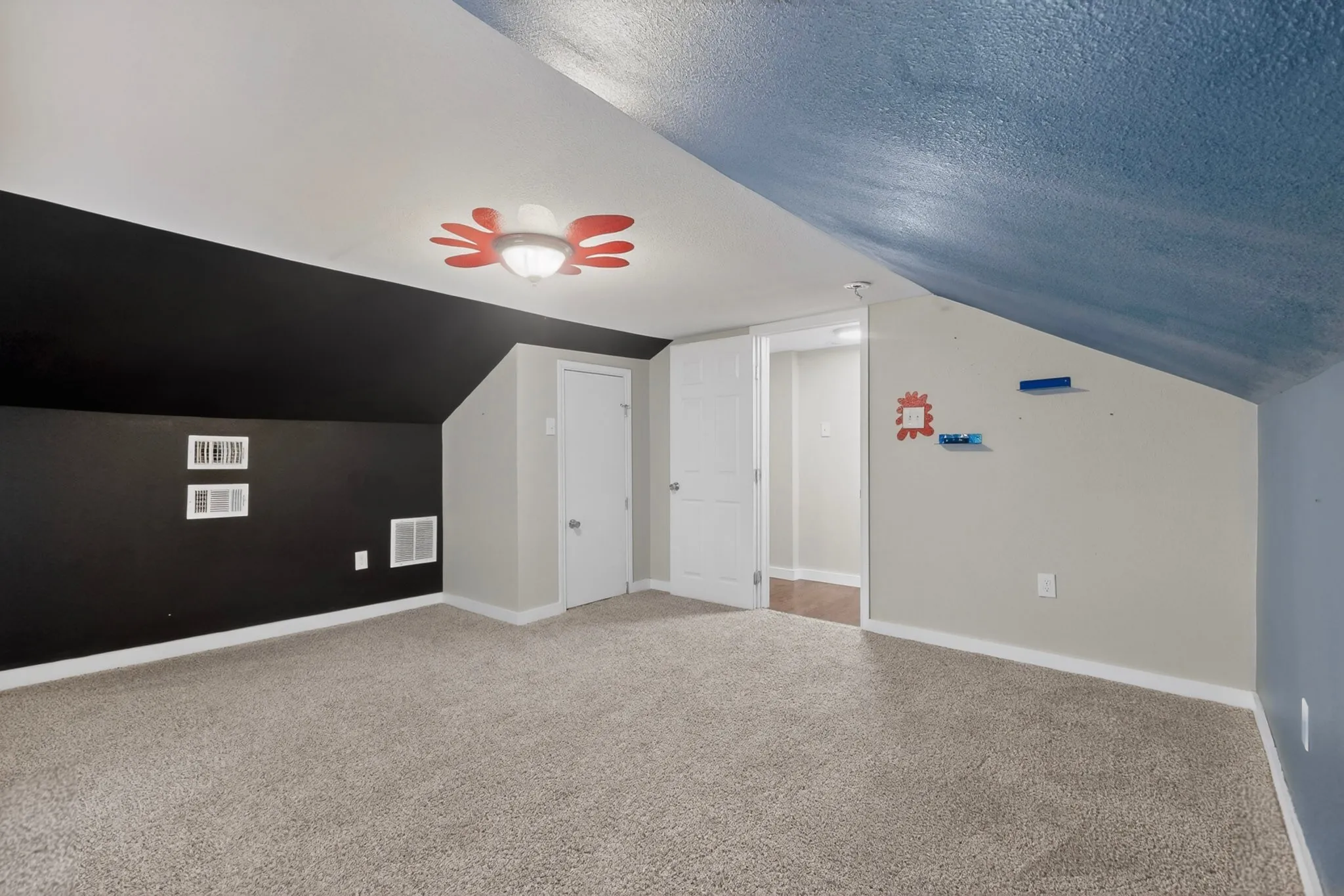 Carpeted room featuring a sloped ceiling, two white panel doors, and a ceiling-mounted light fixture