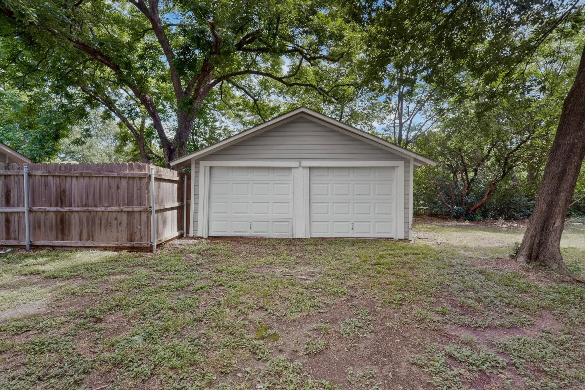 Detached two-car garage with gray siding and white garage doors