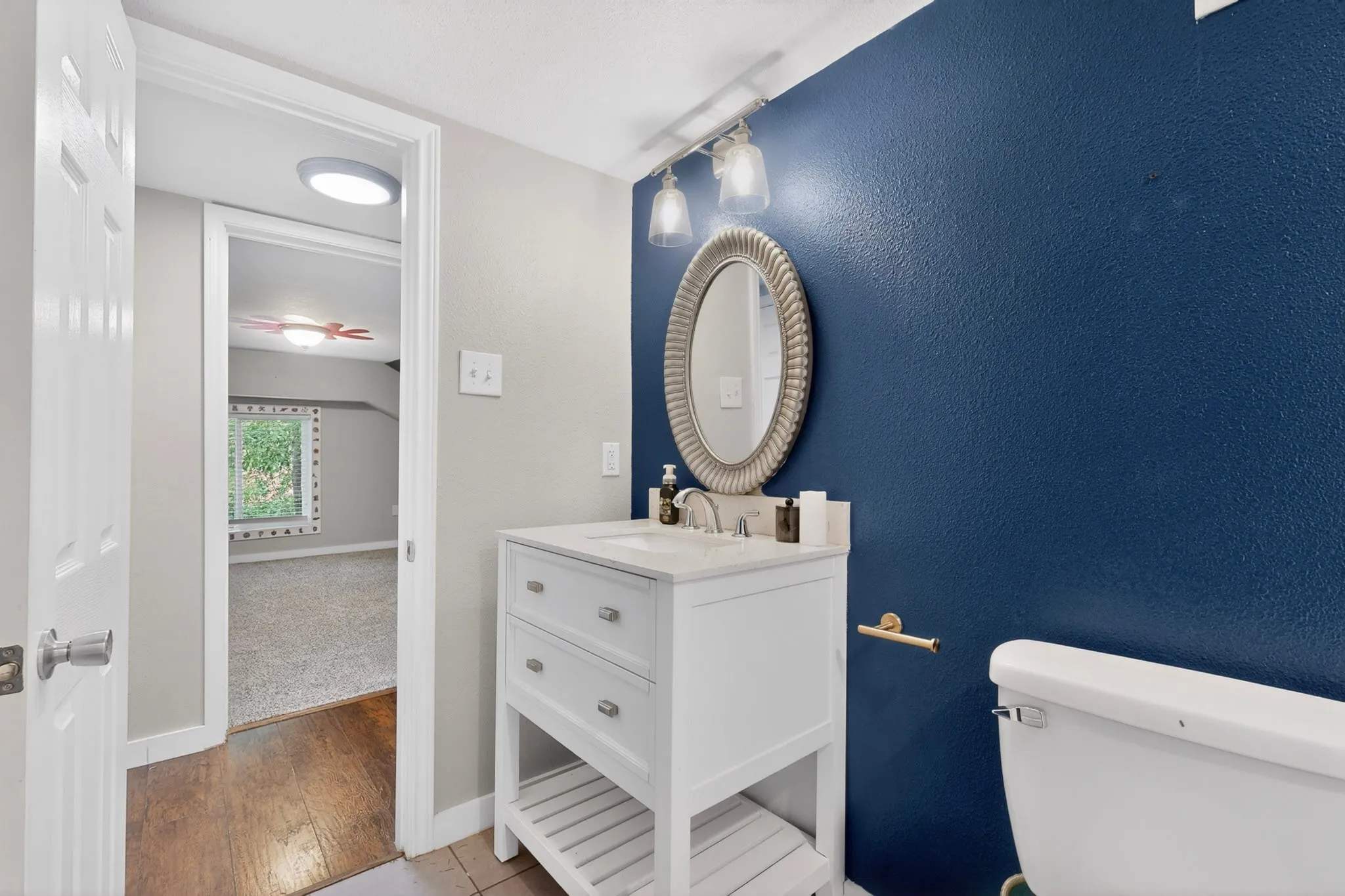 Bathroom featuring a white vanity with a rectangular sink, a polished chrome faucet, and an oval framed mirror