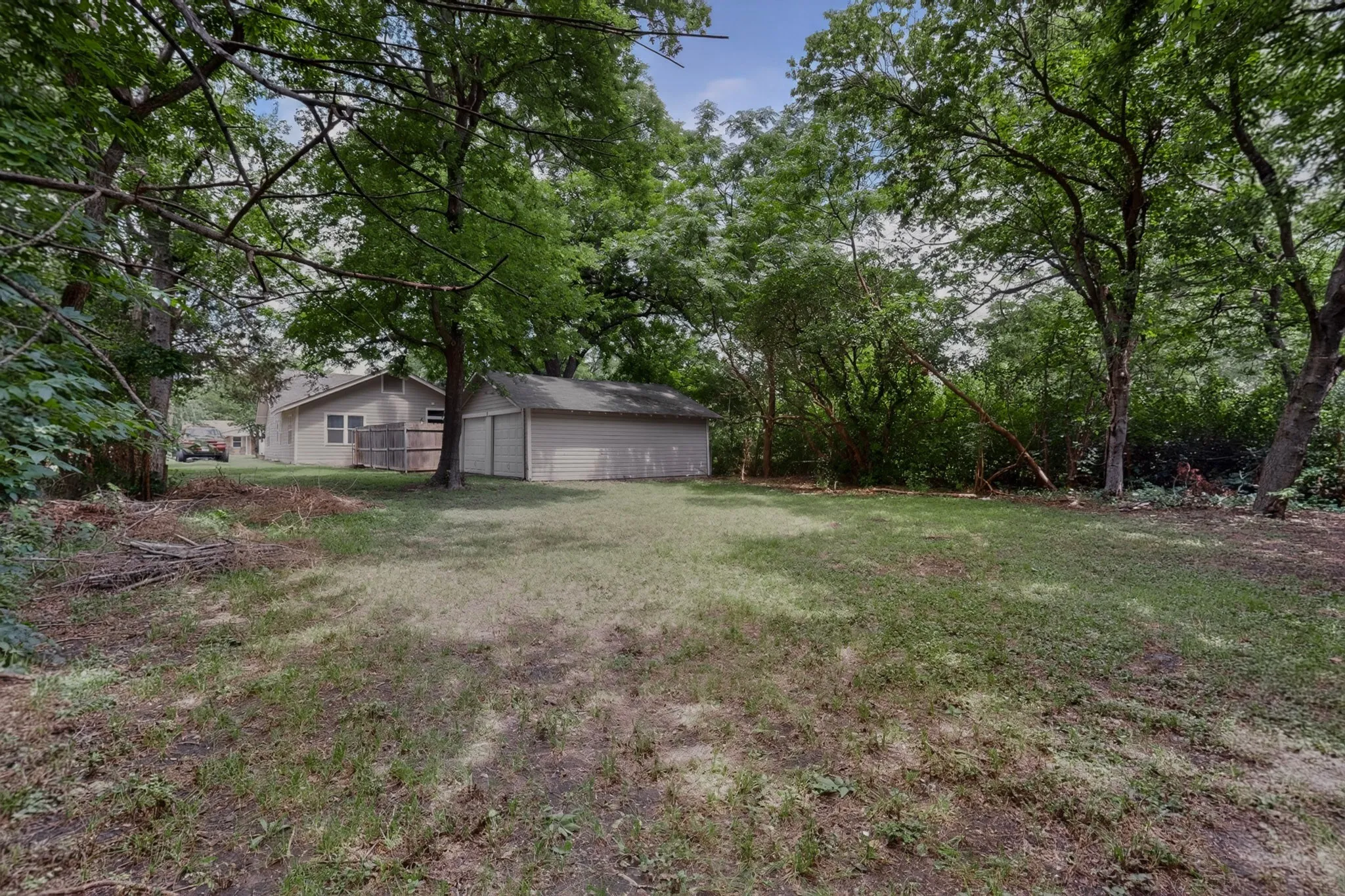 Expansive rear yard featuring mature trees and a detached two-car garage
