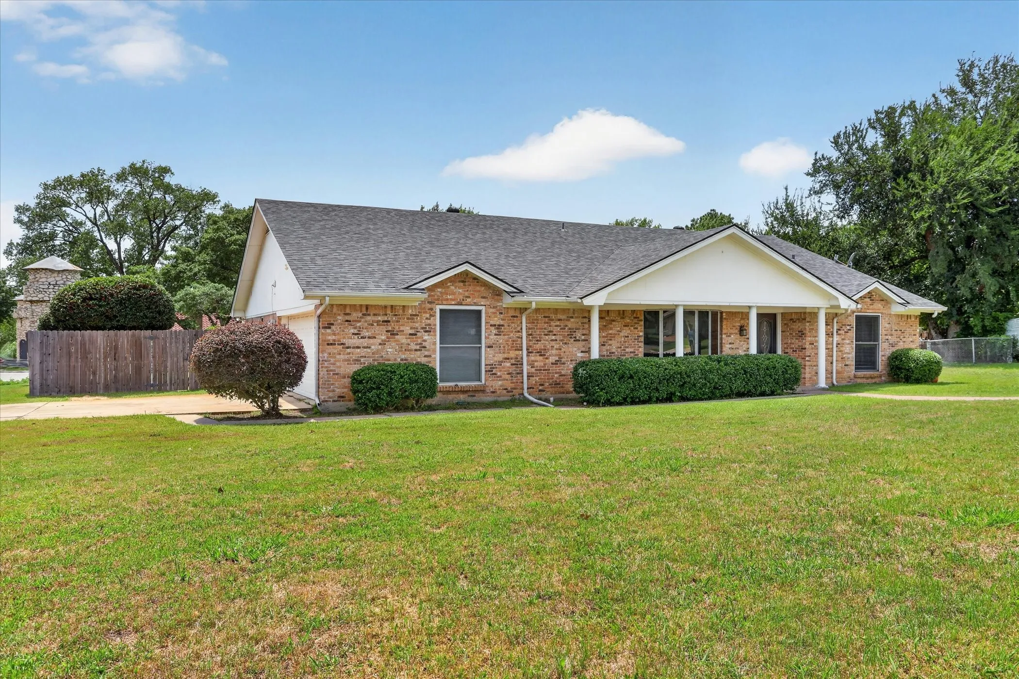 Brick exterior with a gabled roofline covered front porch and large front yard grass