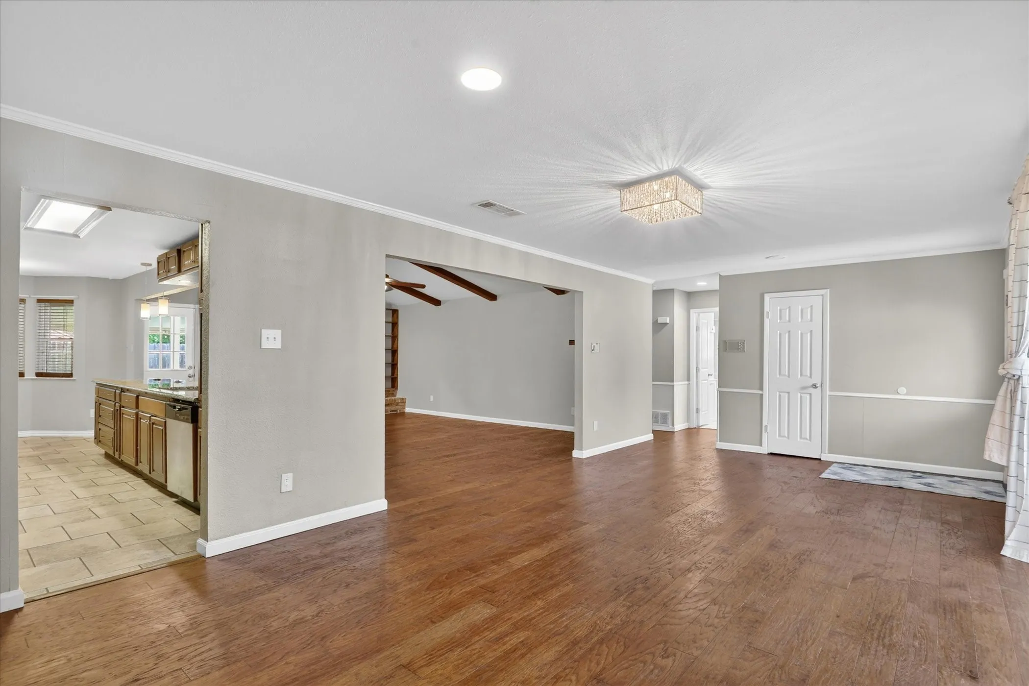 Spacious front room featuring wood-finish flooring, a decorative oval glass door, and a curved window with multiple panes