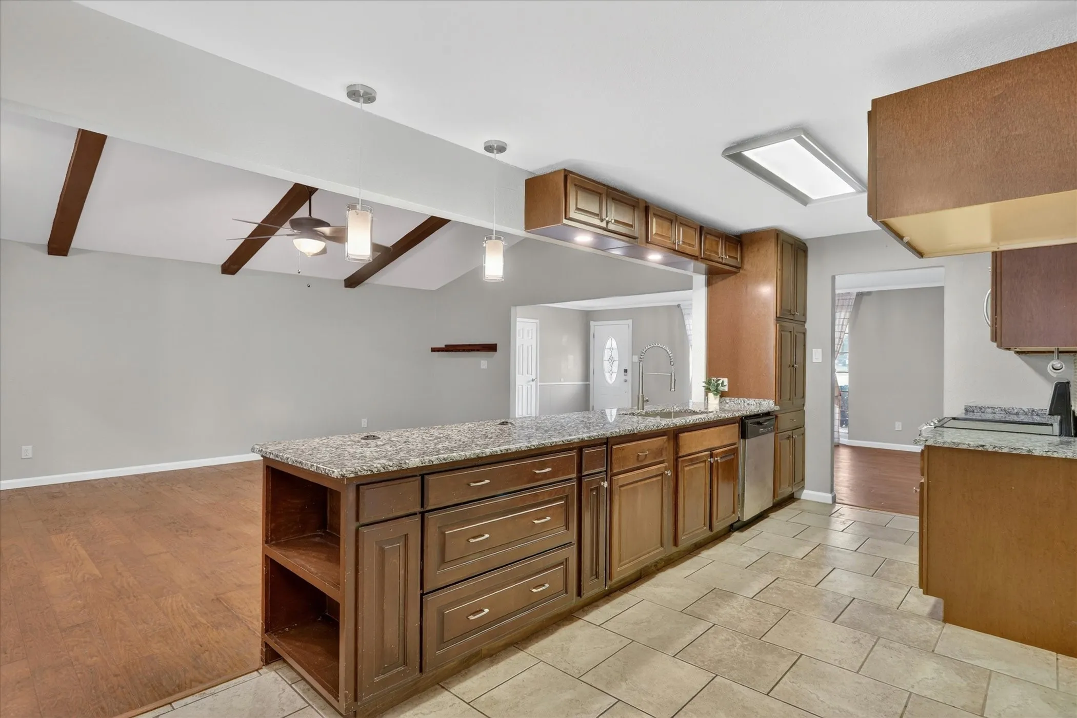 Spacious room featuring wood-finish flooring, light gray walls, two windows with blinds, a ceiling fan with integrated lighting, and white baseboards