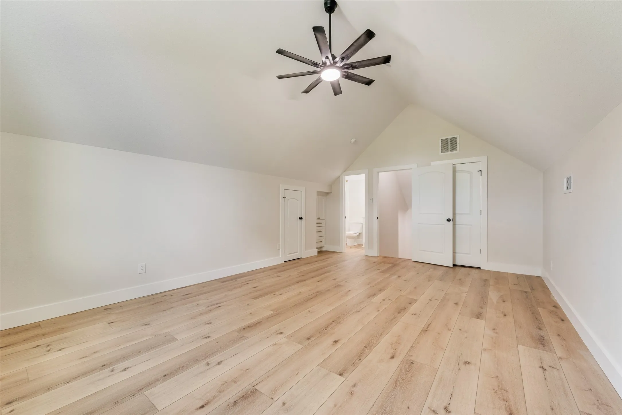 Vaulted ceiling room featuring wood-finish flooring, a modern ceiling fan, and white trim