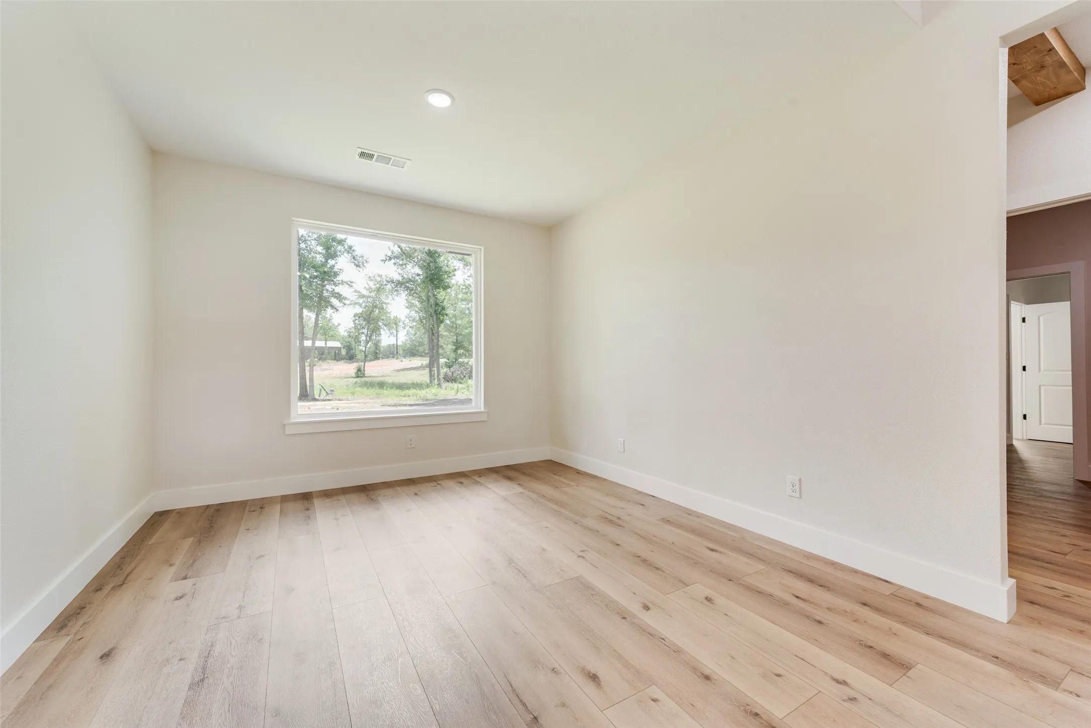 Bright interior space featuring light wood-finish flooring, white baseboards, and a recessed ceiling light