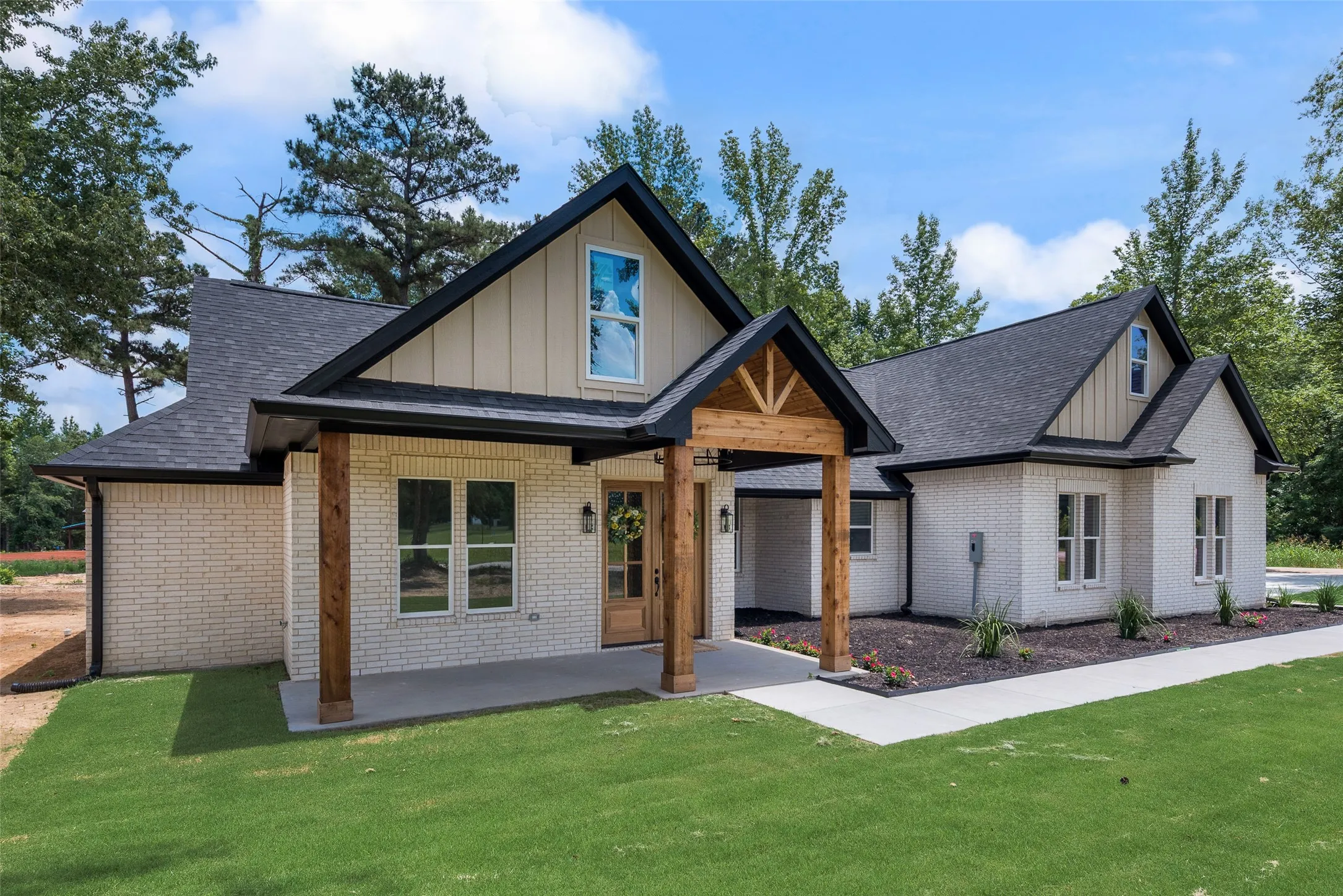 Contemporary residence featuring light-colored brick veneer and dark shingle roofing