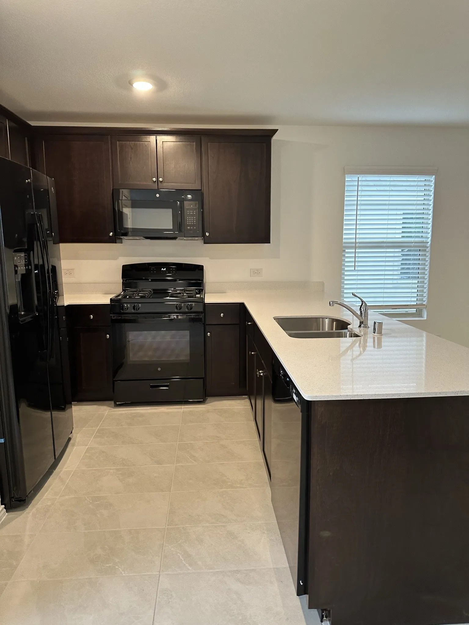 Kitchen featuring dark brown cabinetry, kitchen peninsula, sink, and black appliances