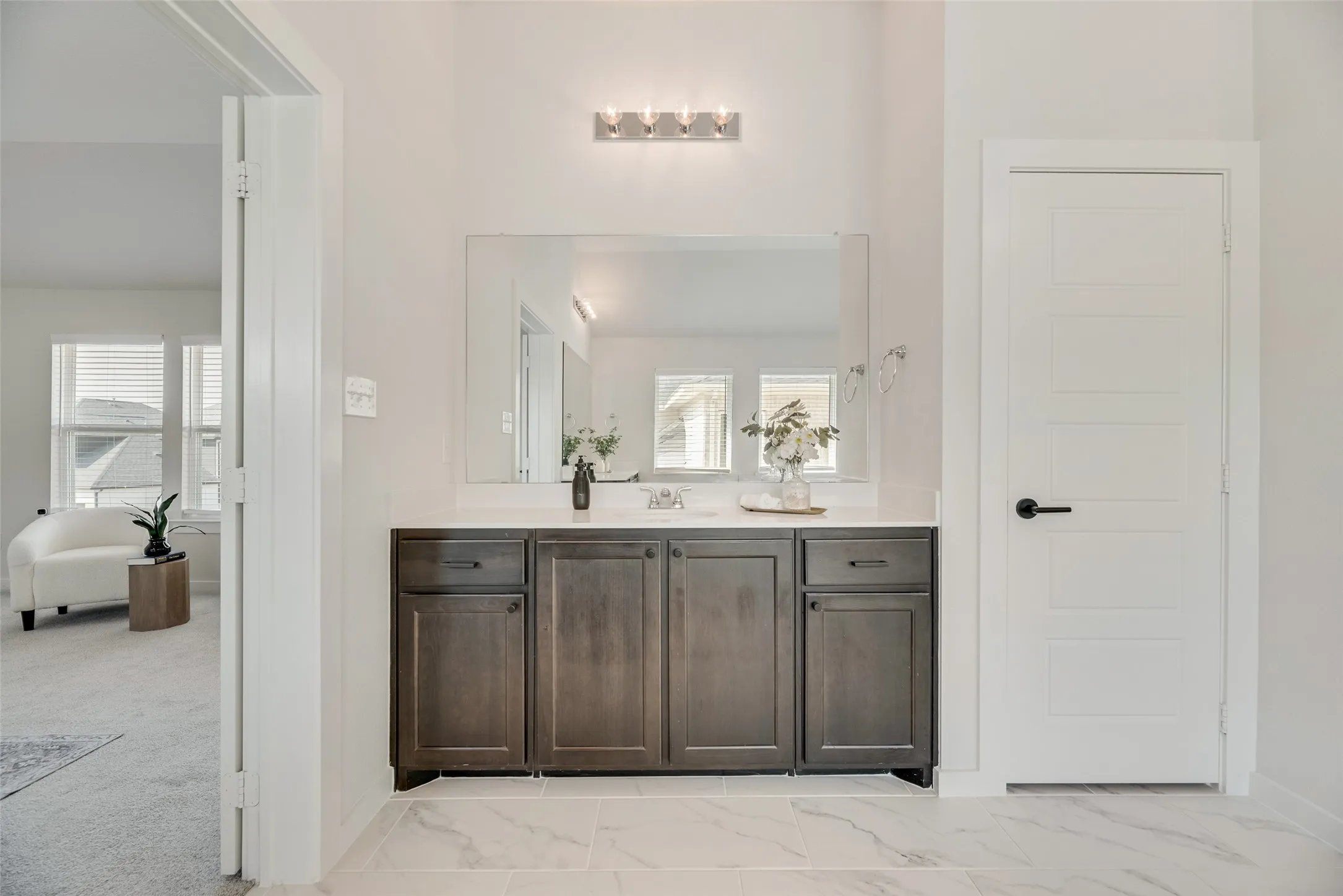 Vanity area featuring a single basin with a light countertop, dark wood-finish cabinetry, and a rectangular mirror
