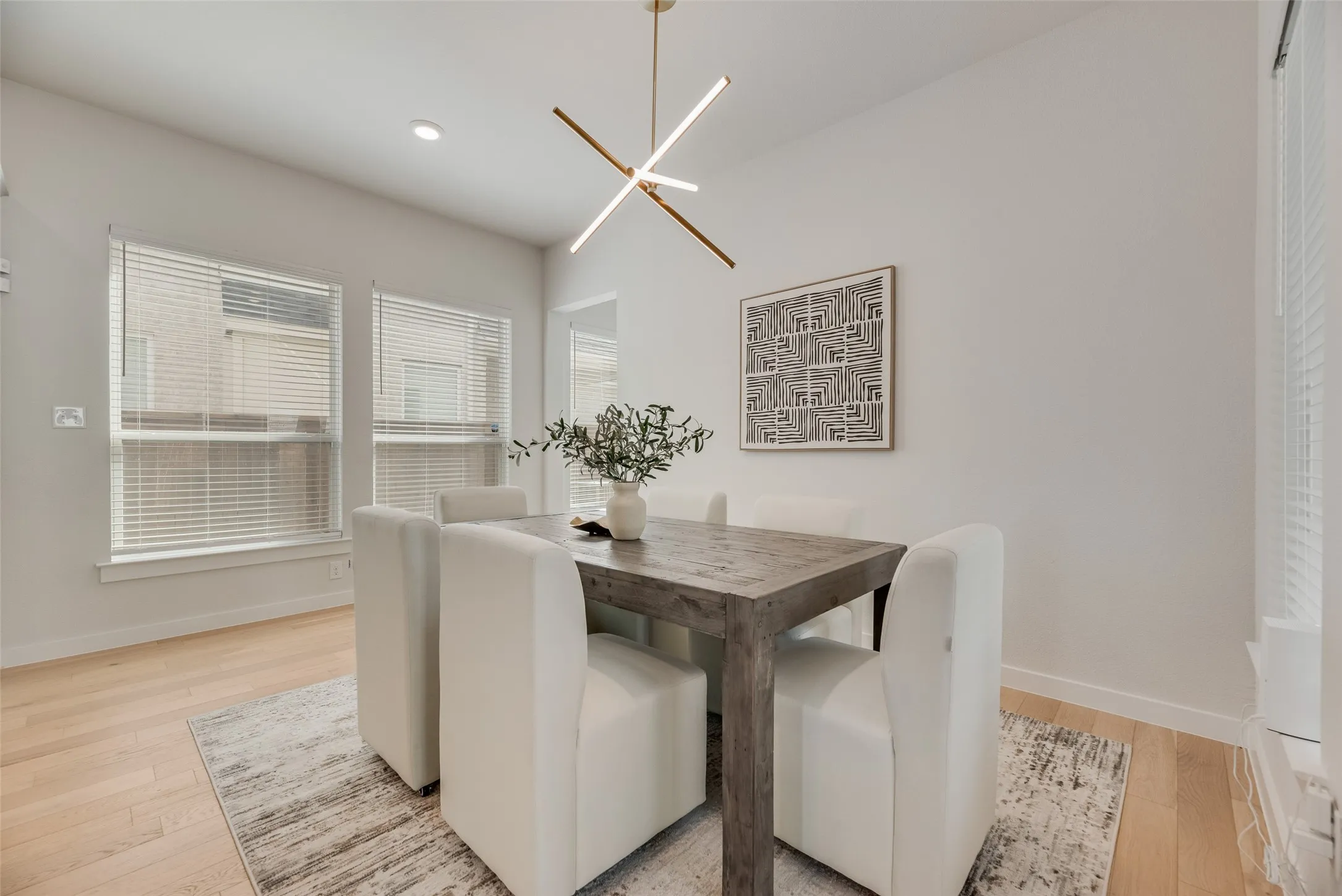 Bright dining area featuring light wood-finish flooring and a modern linear chandelier