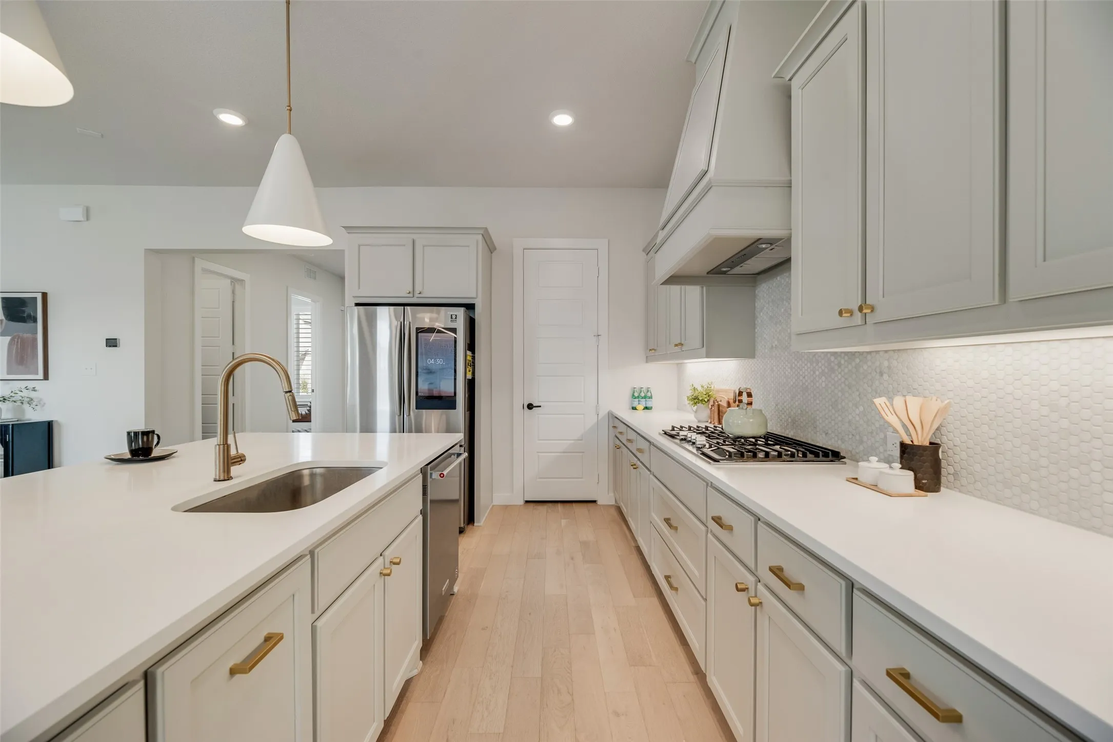 Kitchen featuring a gas range, white hexagon tile backsplash, stainless steel appliances, and light wood-finish flooring