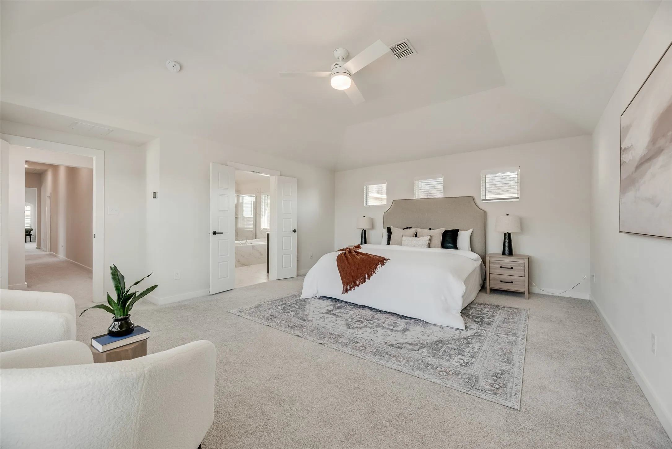 Spacious room featuring light-toned carpeting and a tray ceiling with a flush-mount ceiling fan