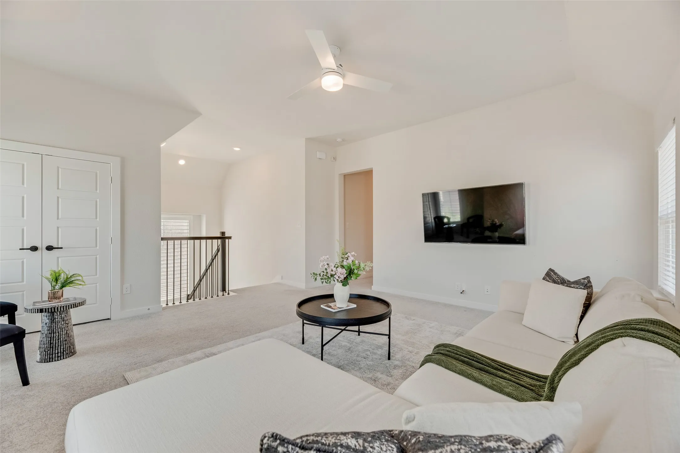 Spacious secondary living area featuring plush carpeting, a modern ceiling fan, and abundant natural light from window blinds