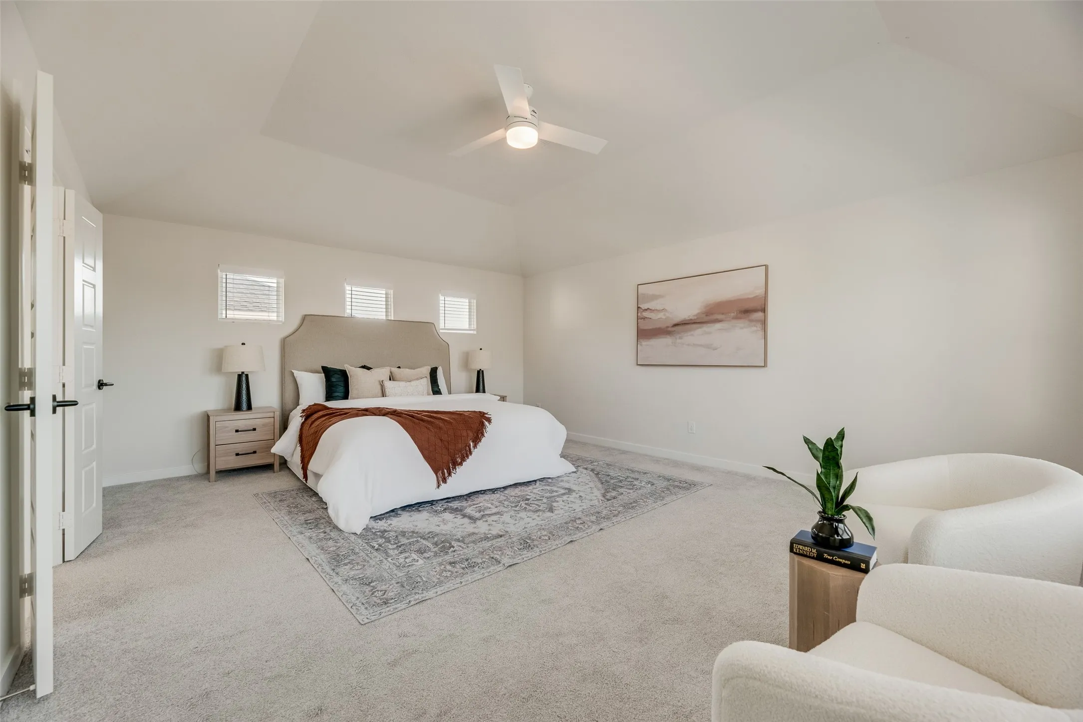 Spacious room featuring vaulted ceilings, light carpeting, and a ceiling fan