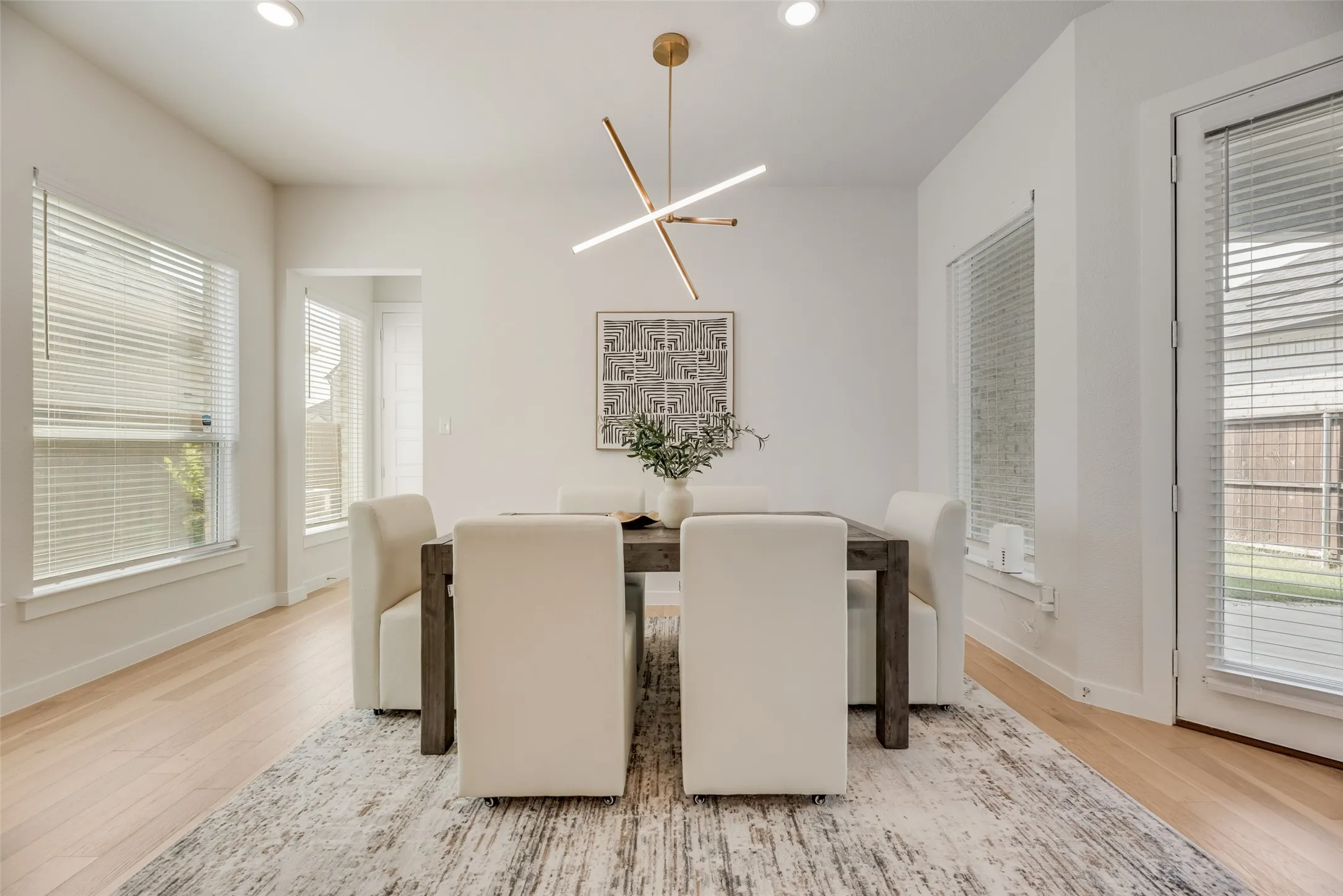 Dining area featuring light wood-finish flooring, recessed lighting, and a contemporary chandelier