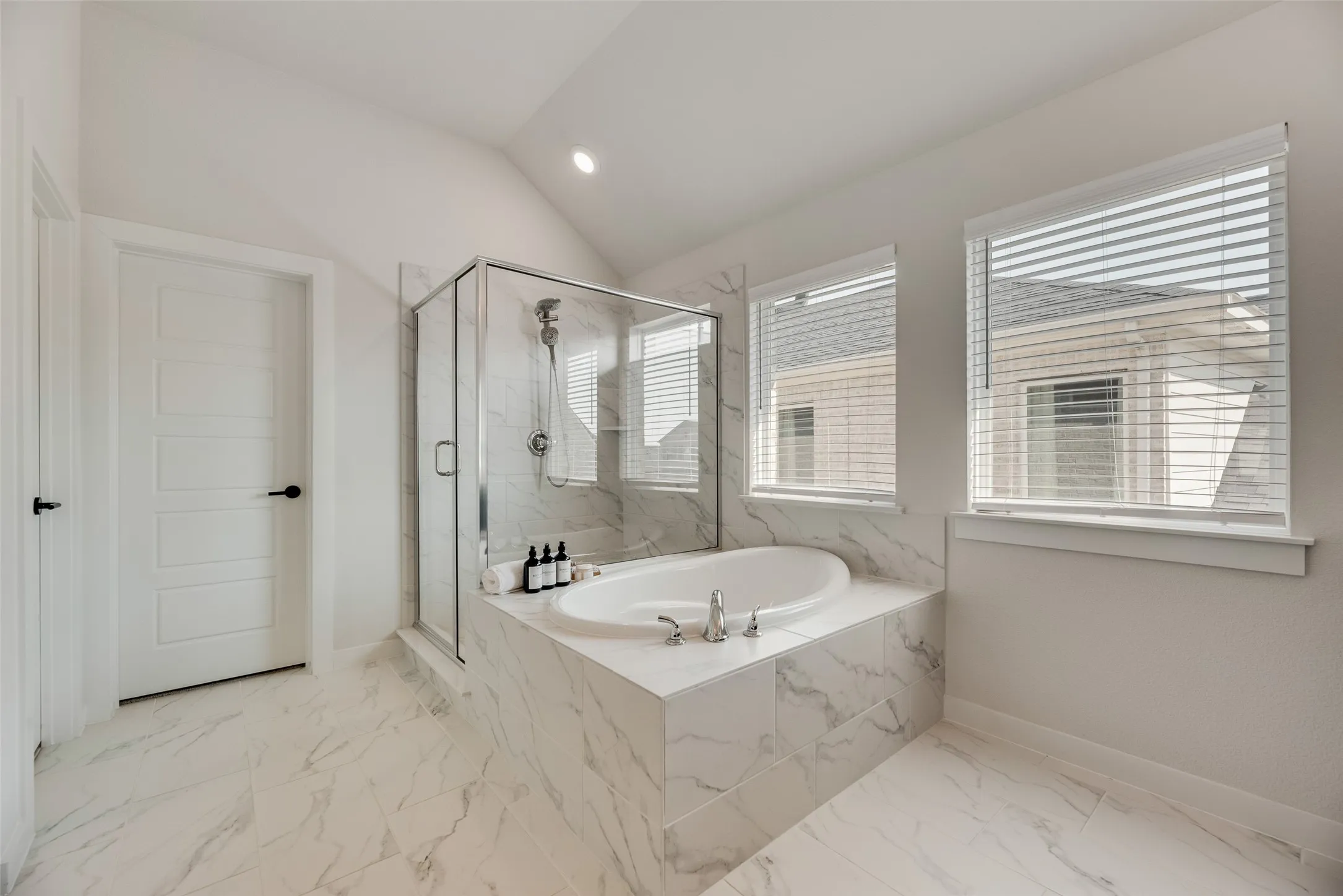Bathroom featuring a built-in soaking tub with deck-mounted fixtures, a glass-enclosed shower, and dual windows with blinds