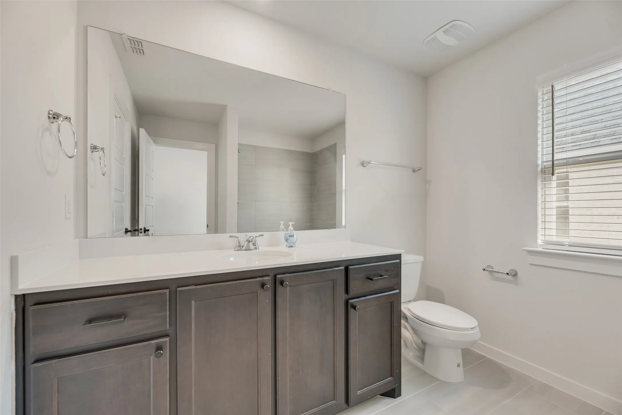 Bathroom featuring a spacious vanity with a white countertop, dark wood-finish cabinetry, and brushed nickel hardware