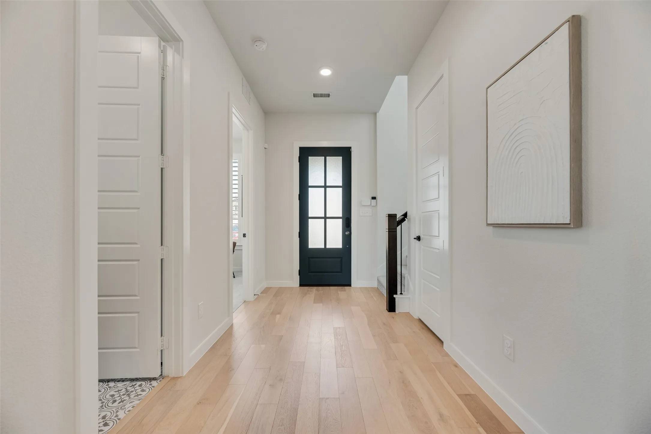 Inviting foyer includes a bathroom and office, as well as a staircase, beautiful white oak floors and ample natural light.