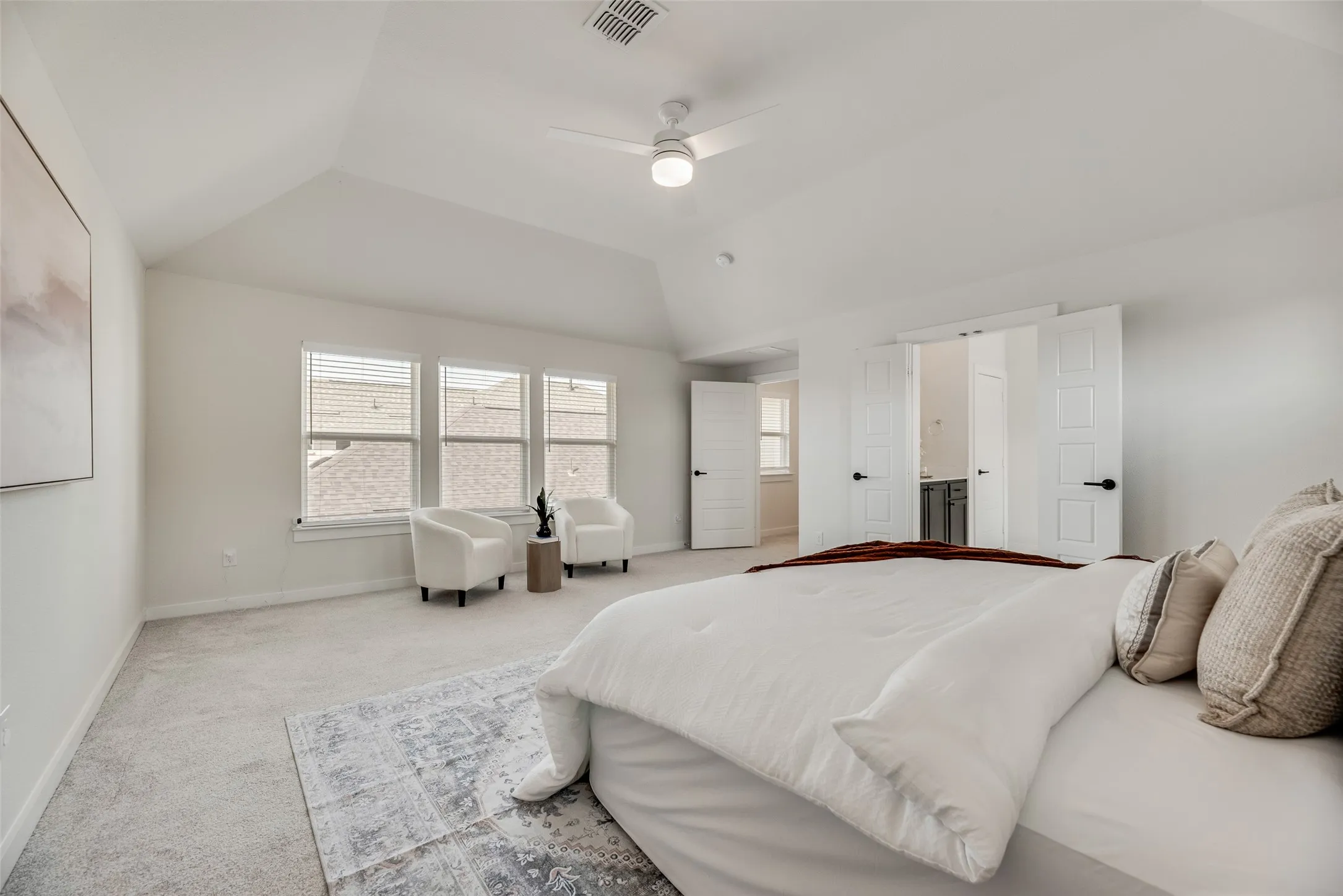 Spacious room featuring vaulted ceilings, light gray carpeting, and a ceiling fan