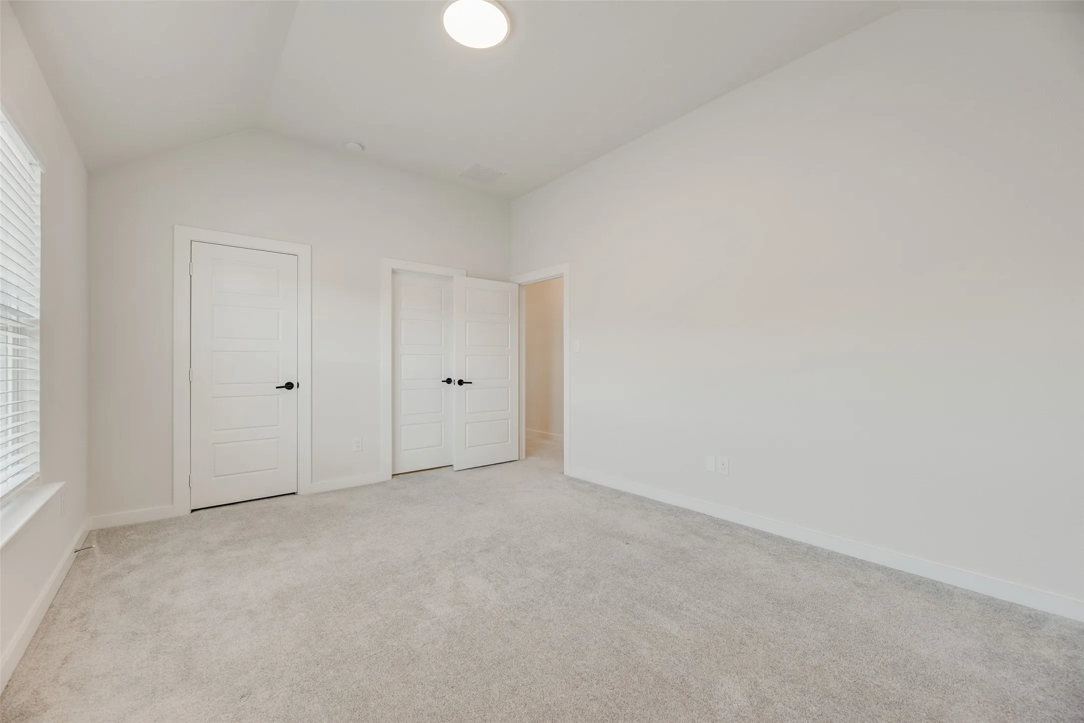 Spacious room with vaulted ceilings and plush grey carpeting