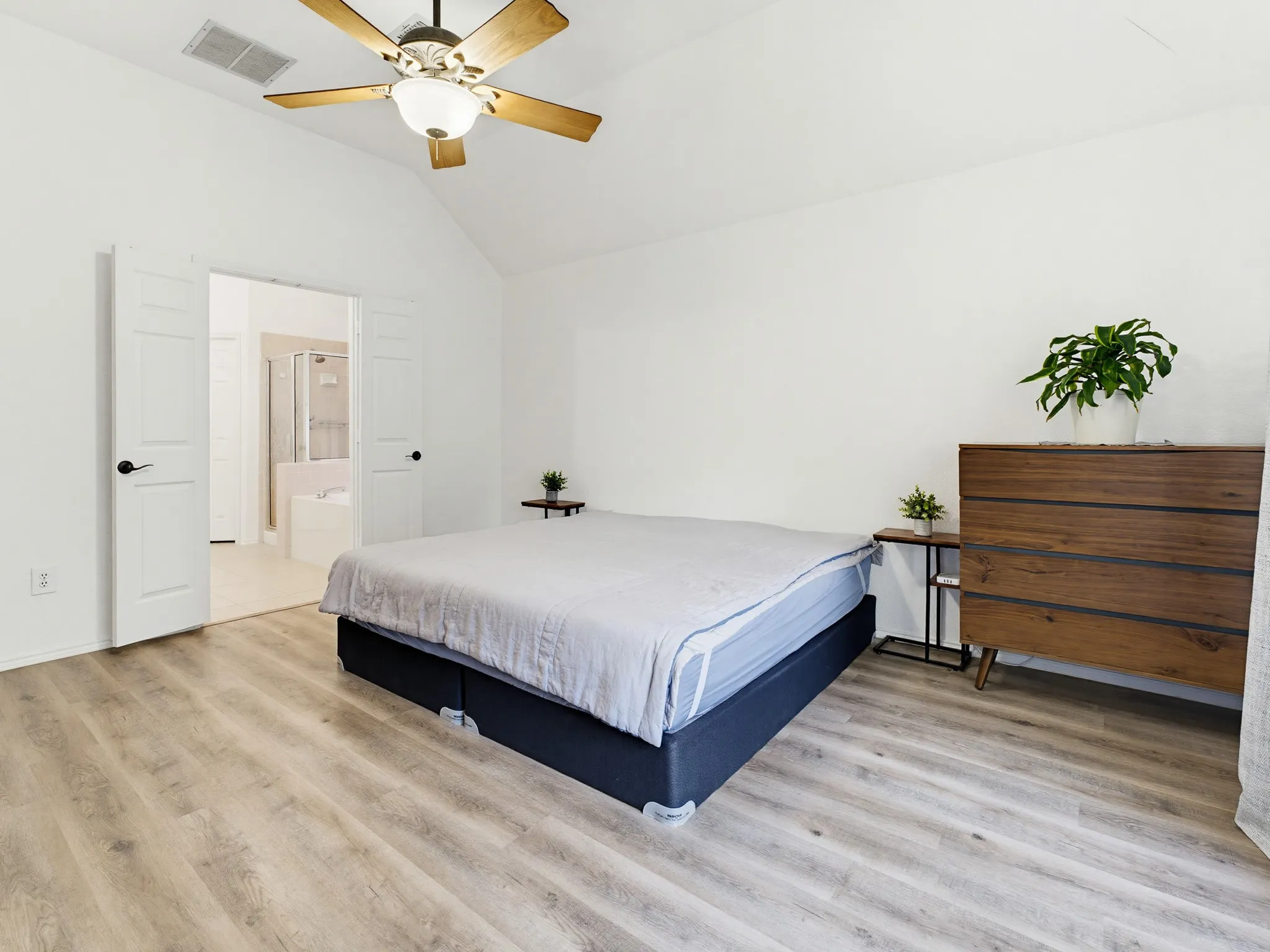 Vaulted ceilings with a ceiling fan overhead, wood-finish flooring, and white walls
