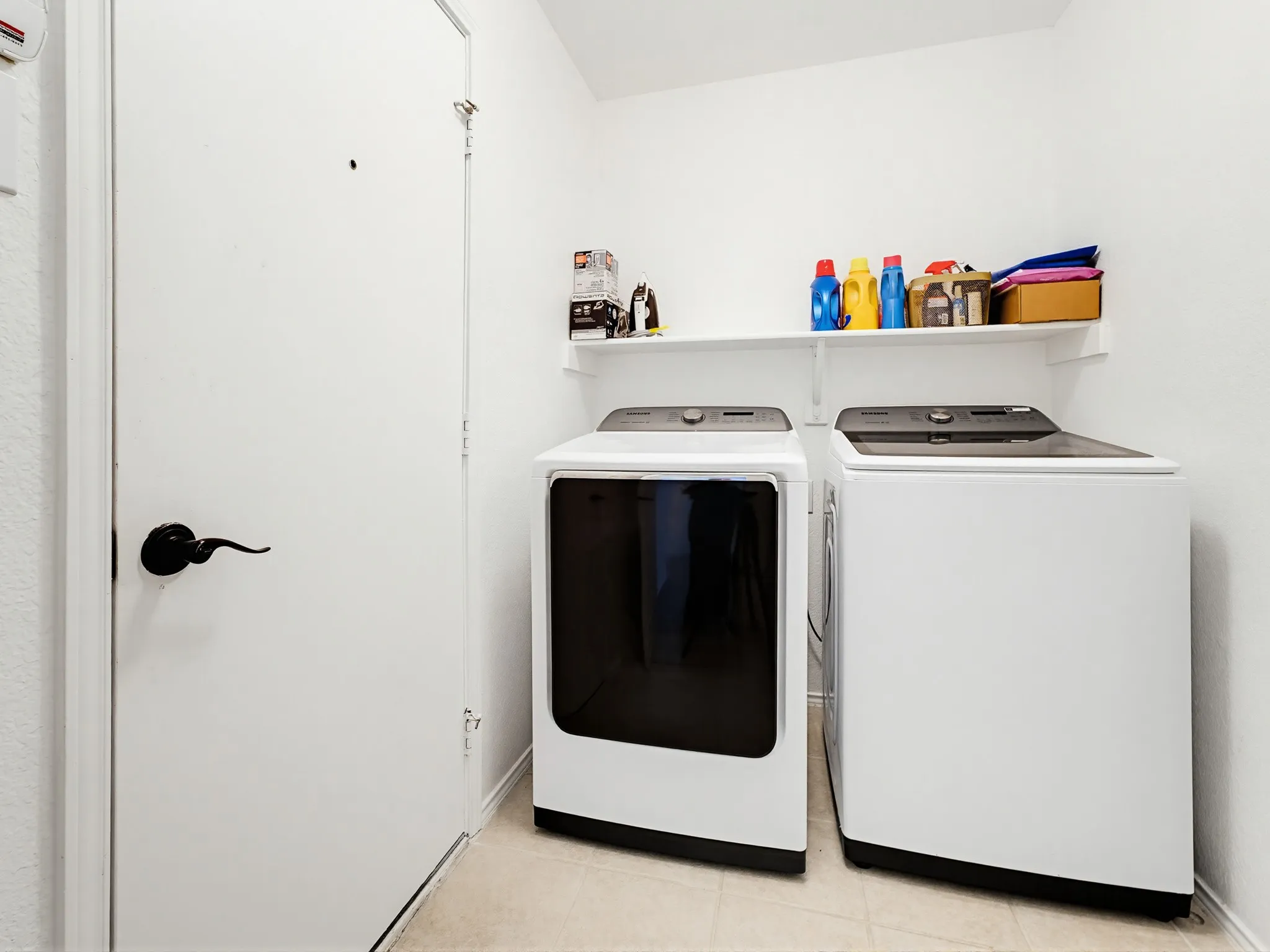 Dedicated laundry space featuring white walls and light-toned flooring
