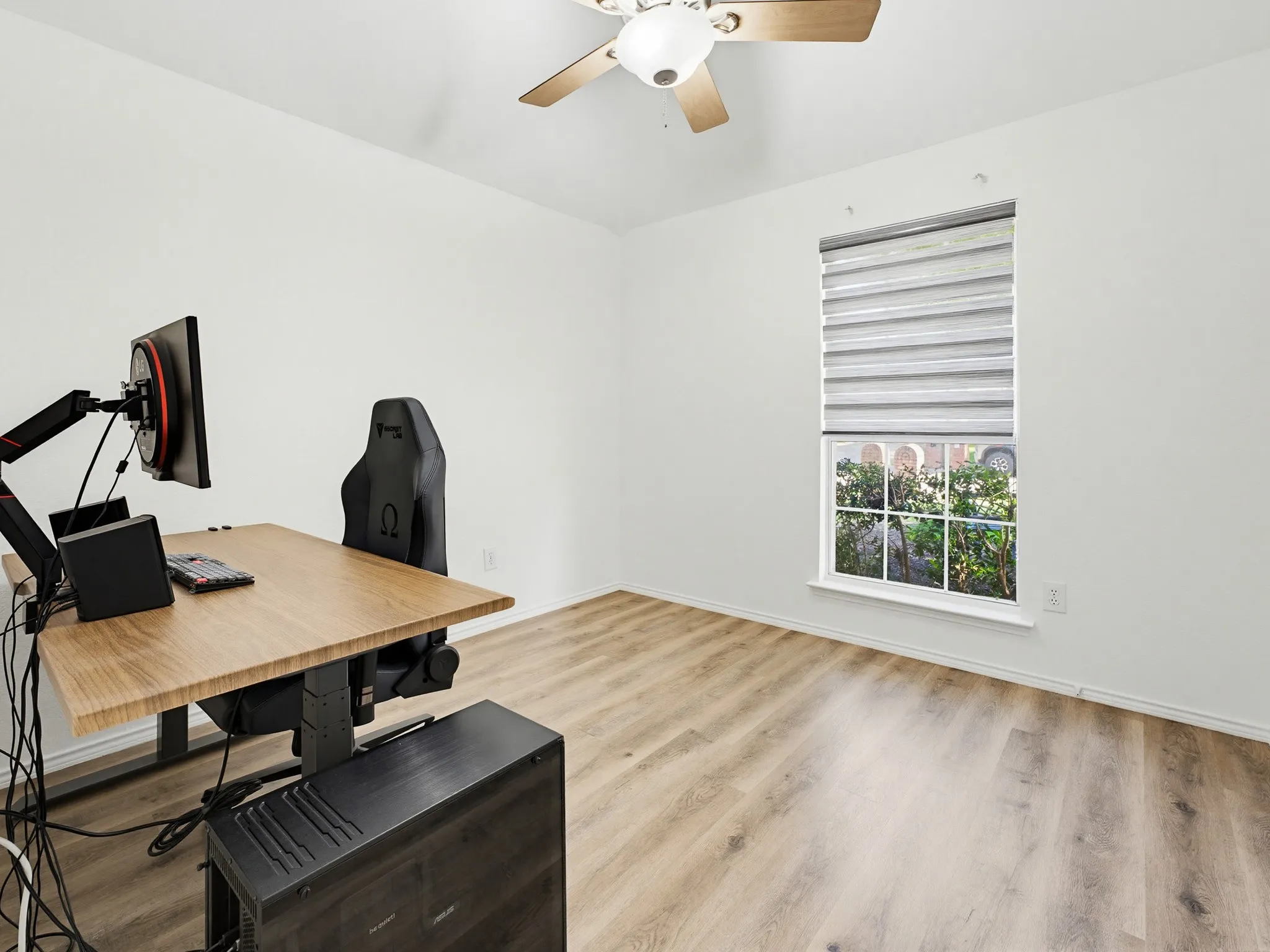 Room featuring wood-finish flooring, white walls, and a window with blinds
