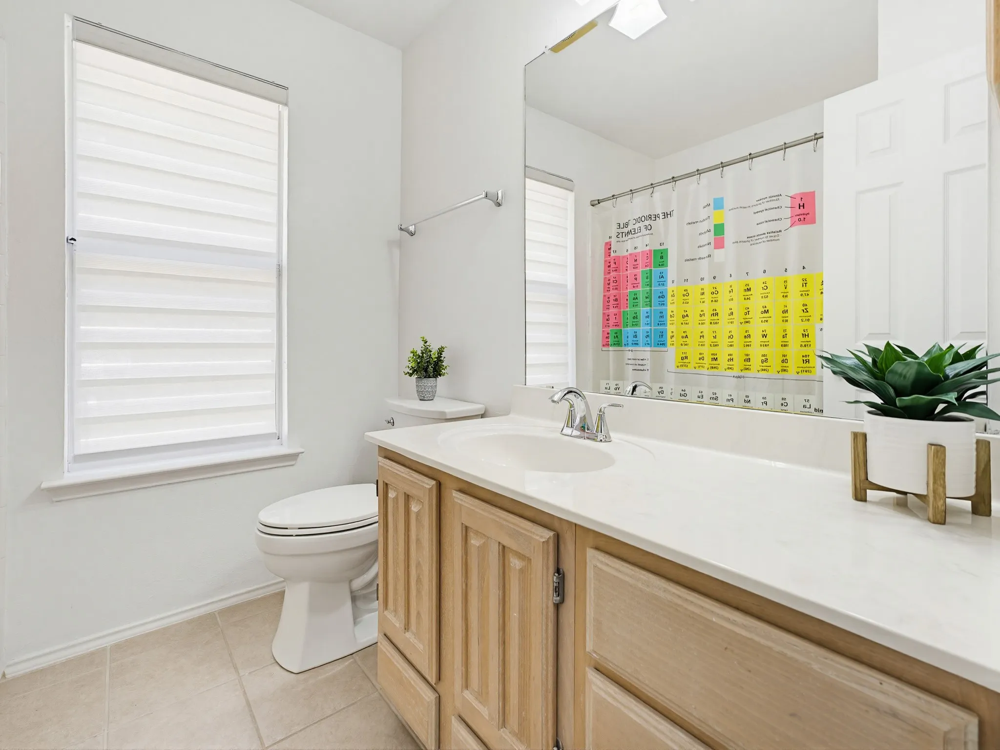 Bathroom featuring a wood-finish vanity with a light-toned countertop and an integrated sink