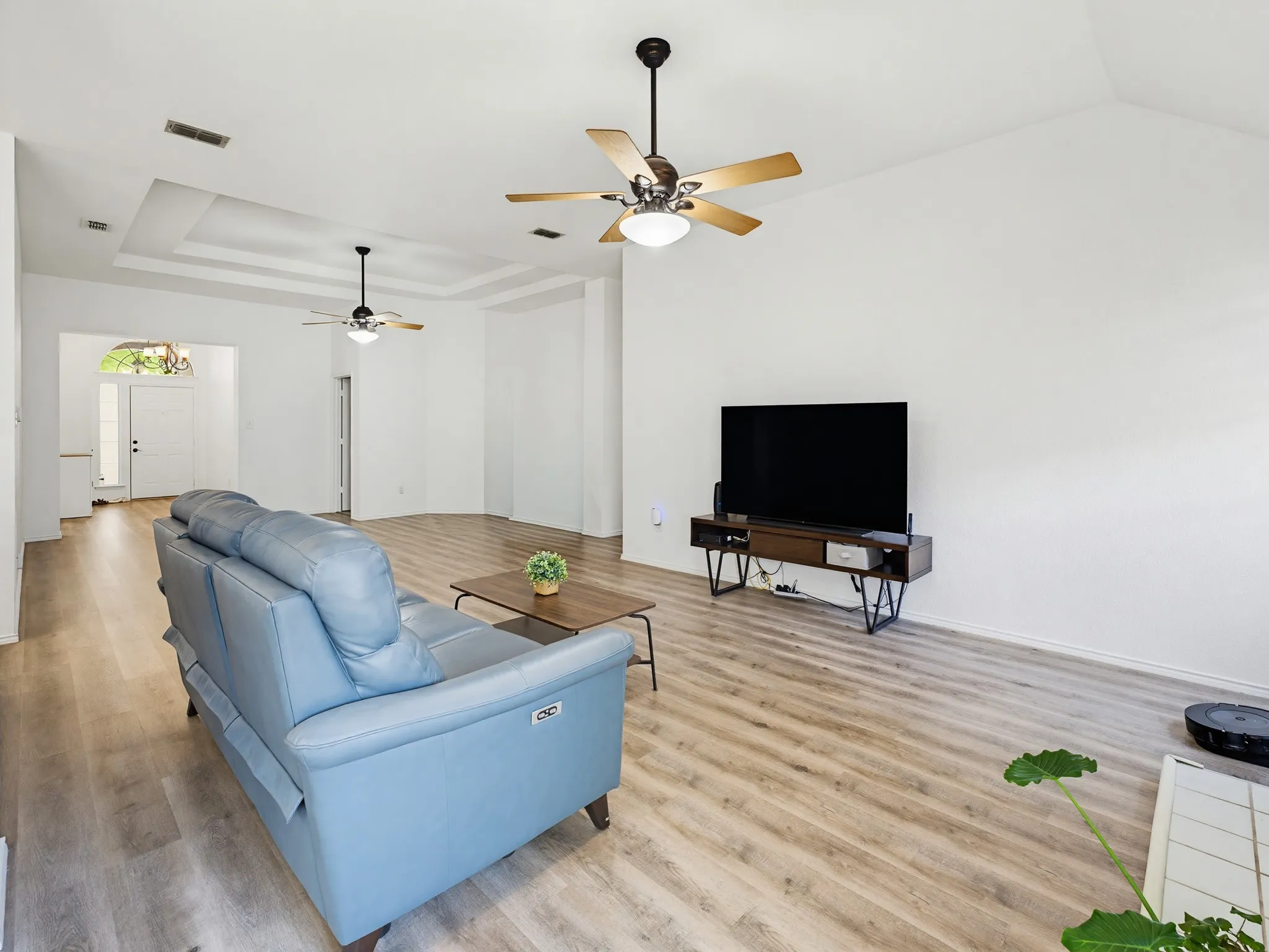 Spacious living area featuring vaulted ceilings, wood-finish flooring, and multiple ceiling fans