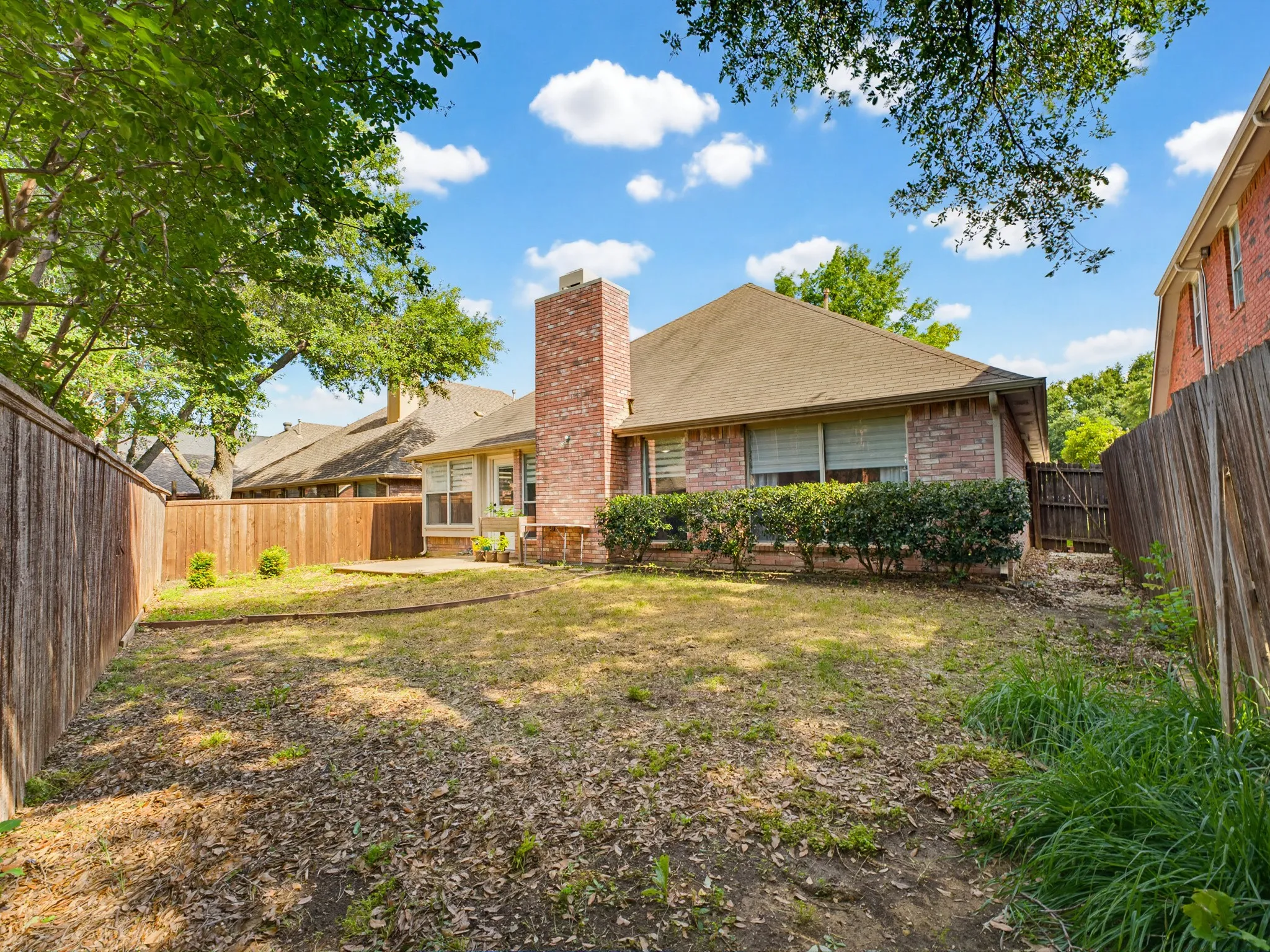 Expansive private backyard featuring a wood fence perimeter, a concrete patio, and mature tree coverage