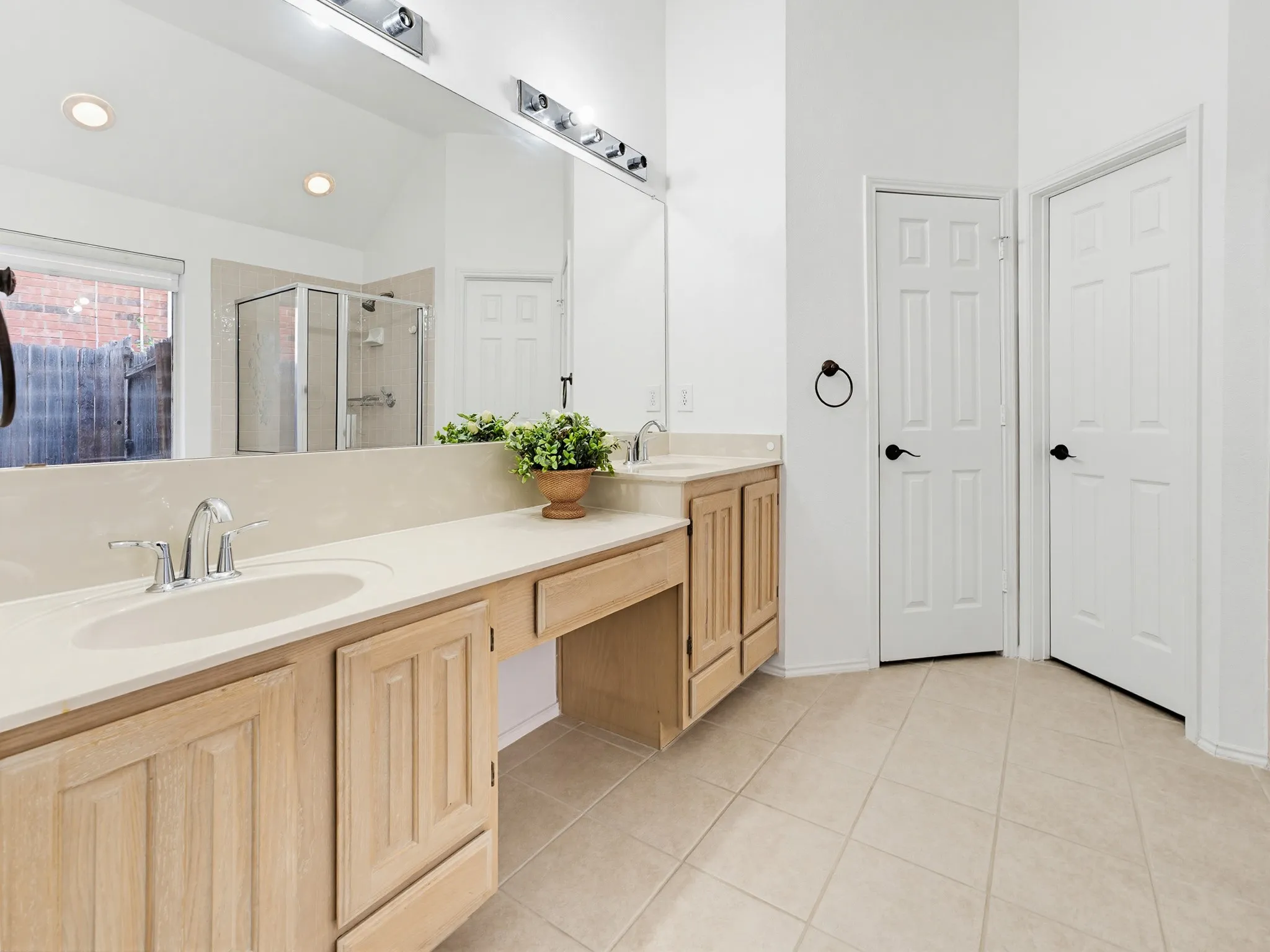 Bathroom featuring dual vanities with integrated sinks, light-toned countertops, and wood-finish cabinetry